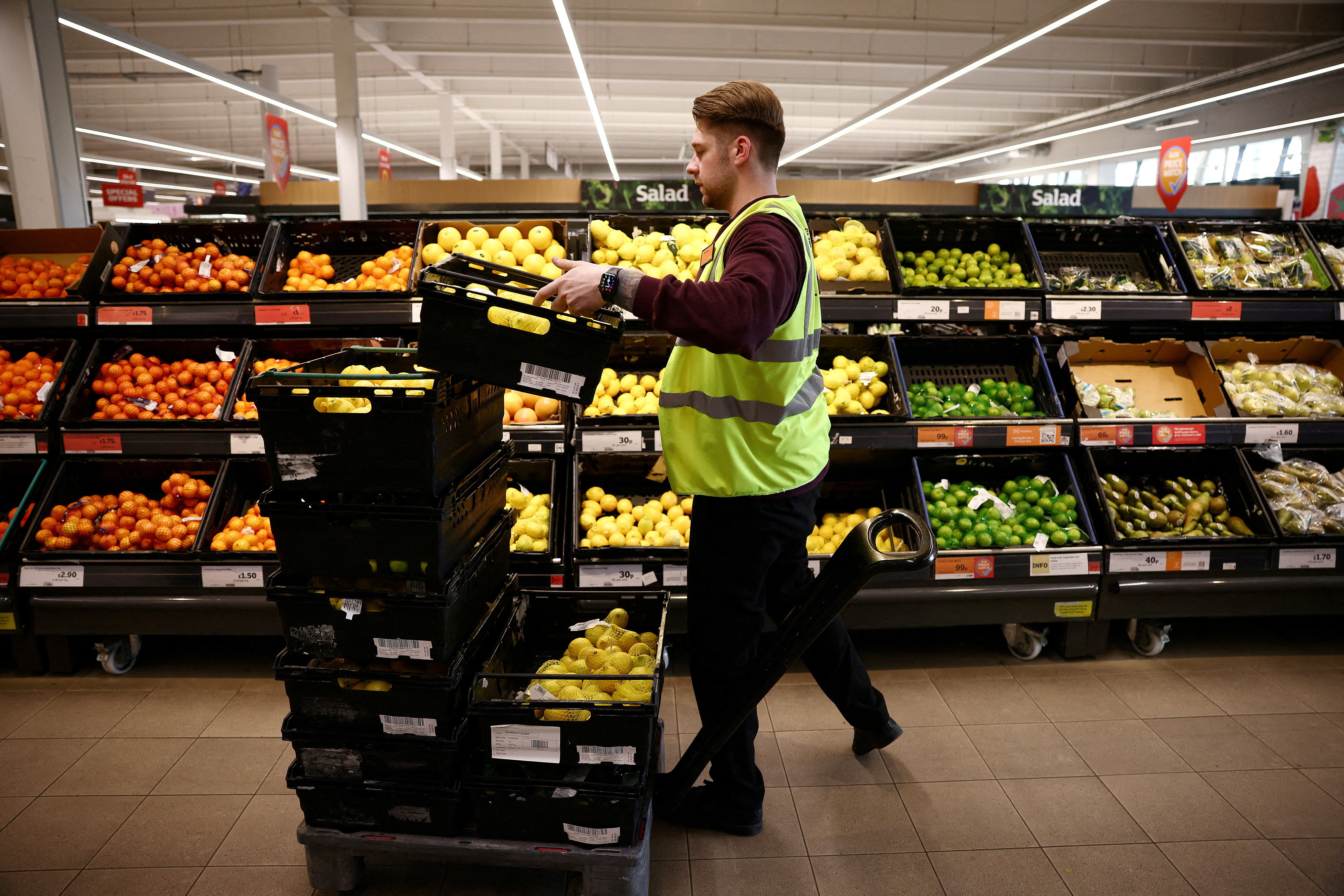 An employee arranges produce inside a Sainsbury’s supermarket in Richmond, west London