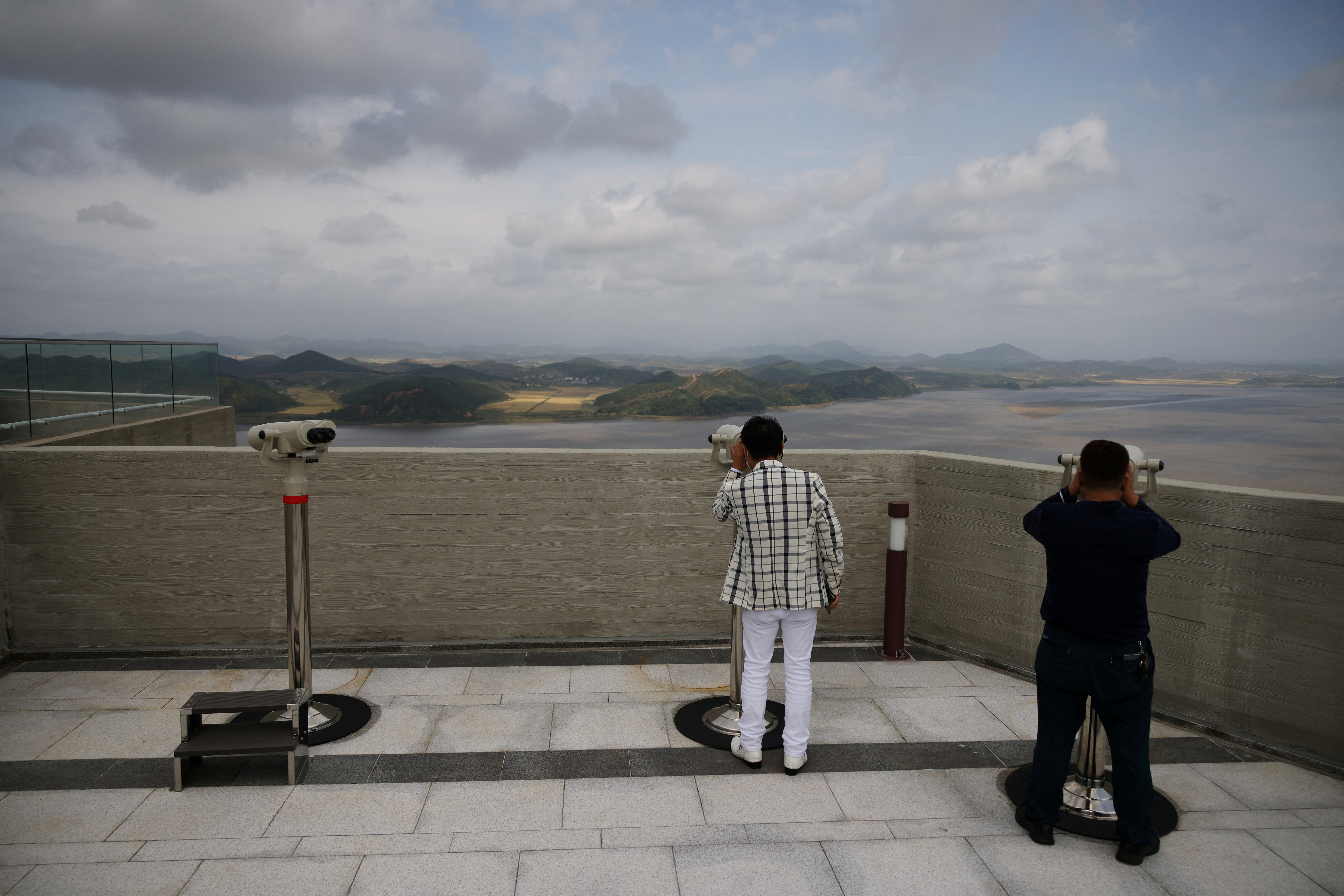 People look at North Korea's propaganda village Kaepoong through pairs of binoculars from the top of the Aegibong Peak Observatory, in Gimpo