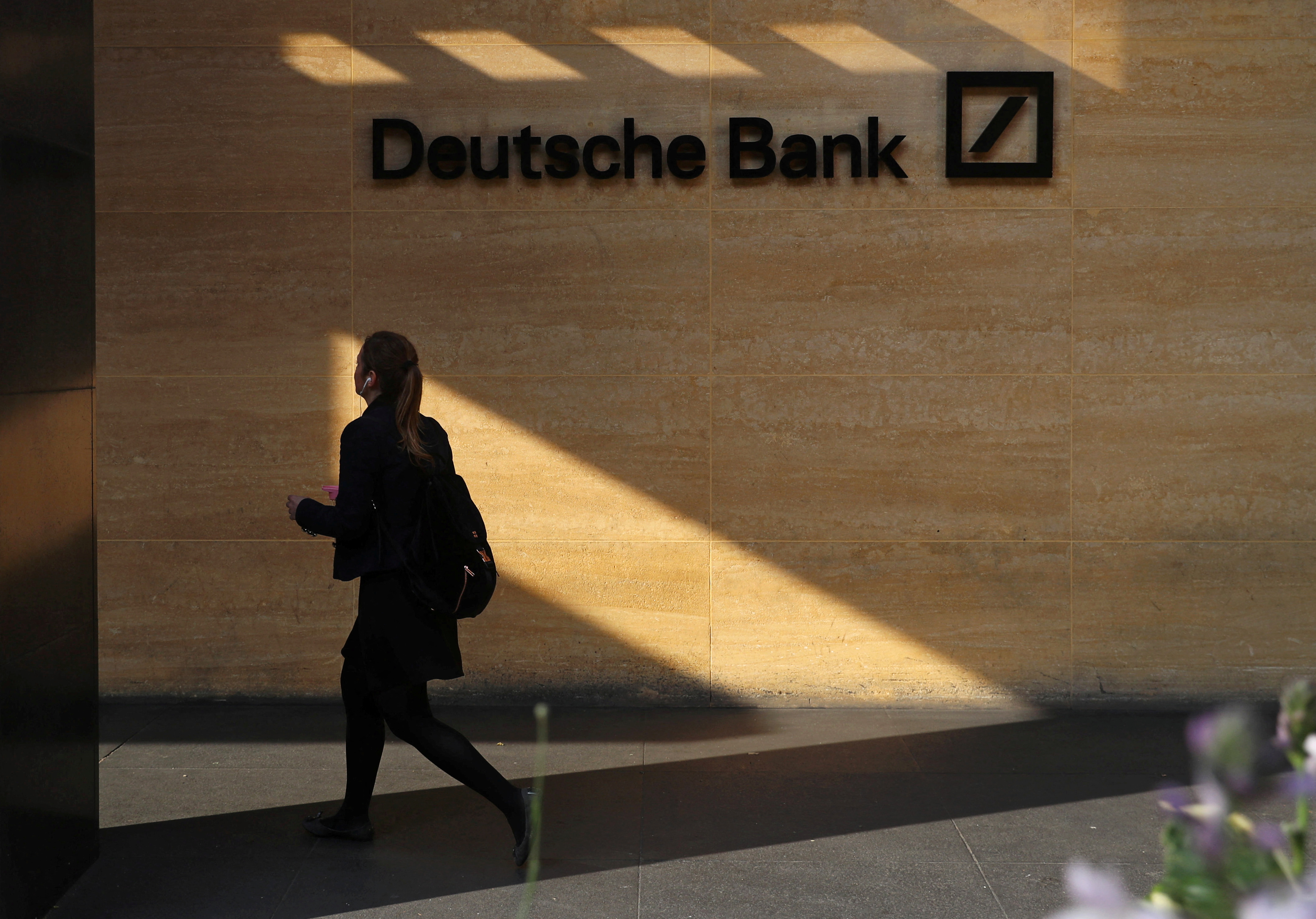 A woman walks past a Deutsche Bank office in London