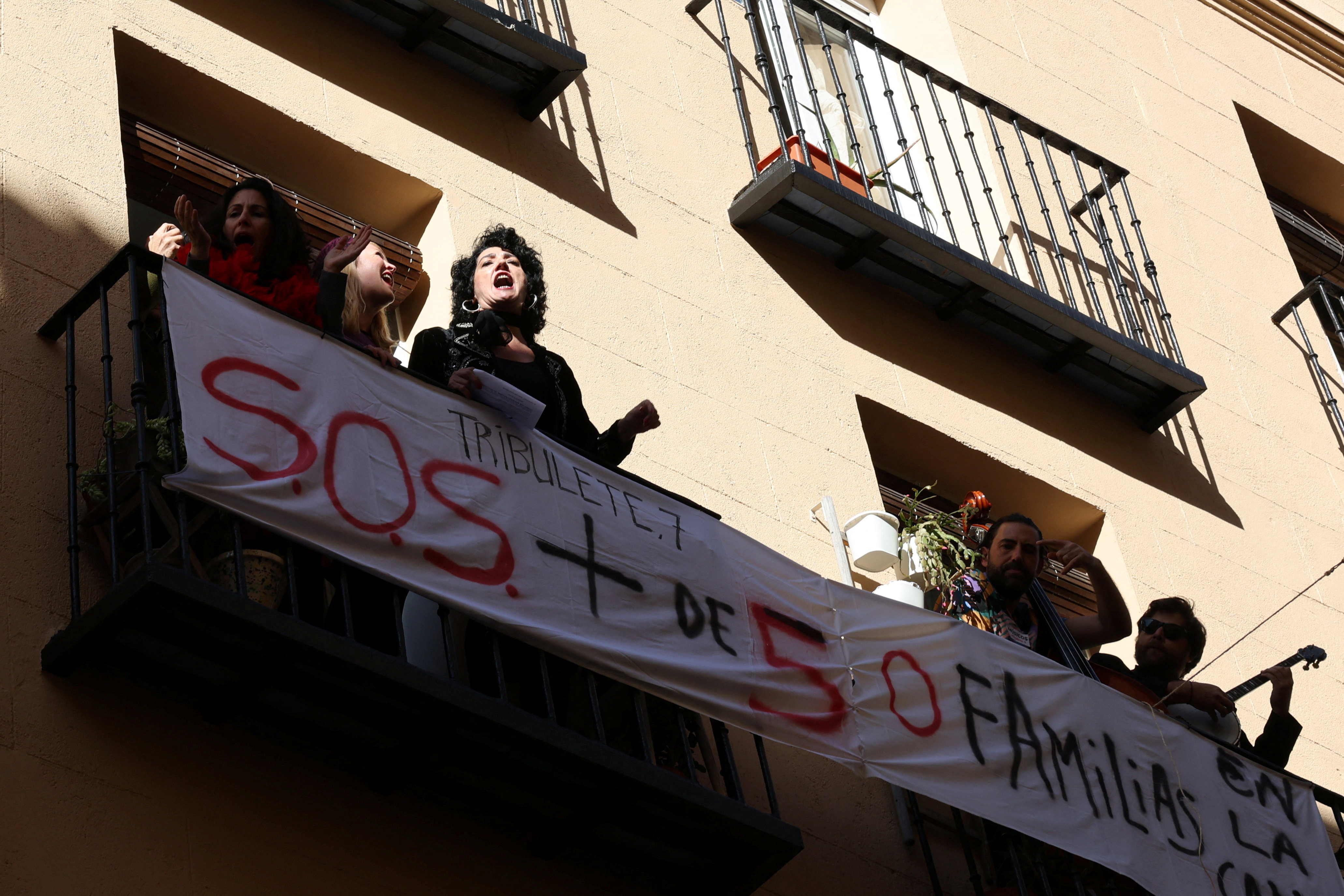 Artists perform during a protest action, in a balcony facing a building whose residents fear they will be evicted in the event of its purchase by a real estate investment fund, in Madrid