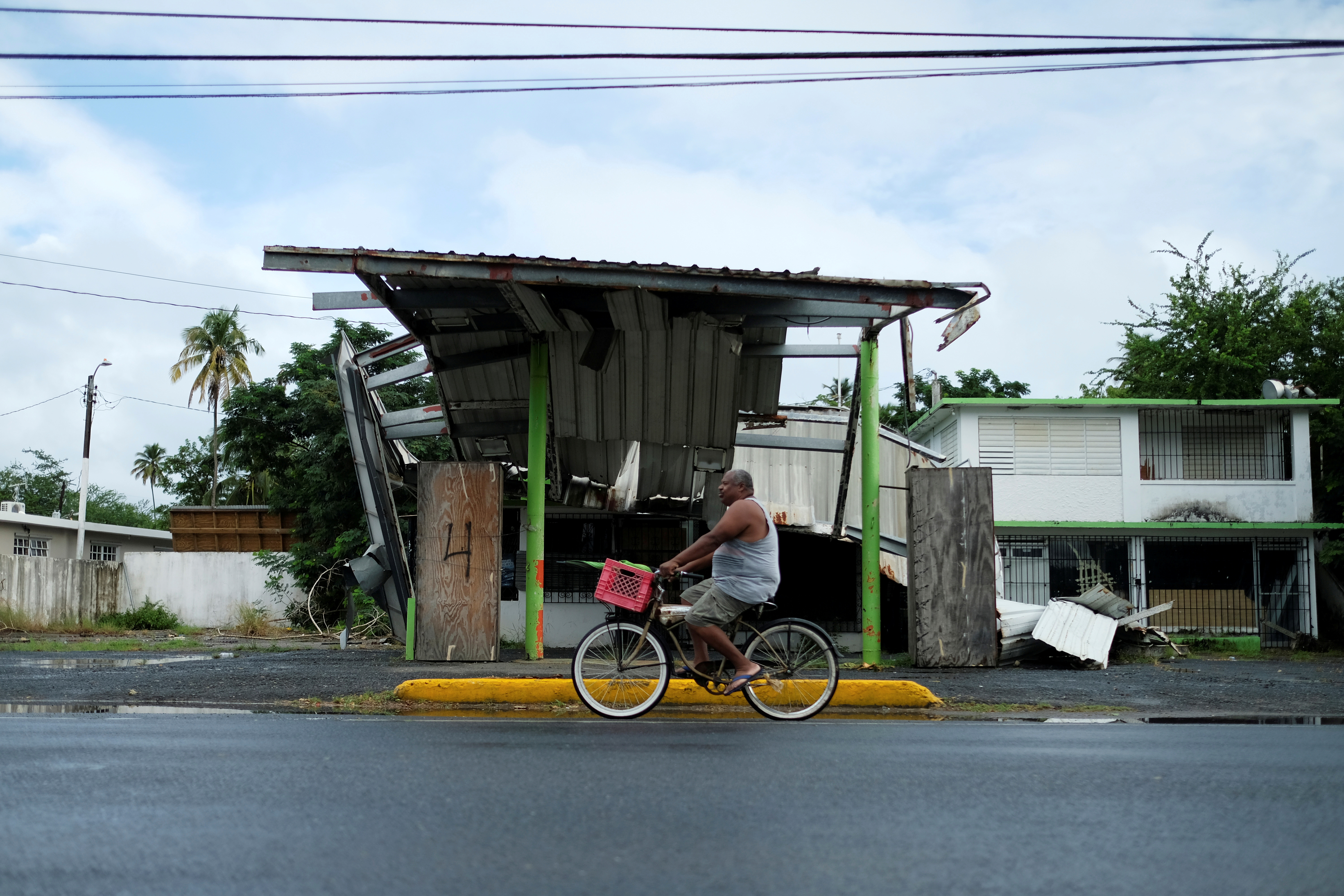 A man rides his bicycle past a gas station that was damaged by Hurricane Maria two years ago, as Tropical Storm Karen approaches in Loiza