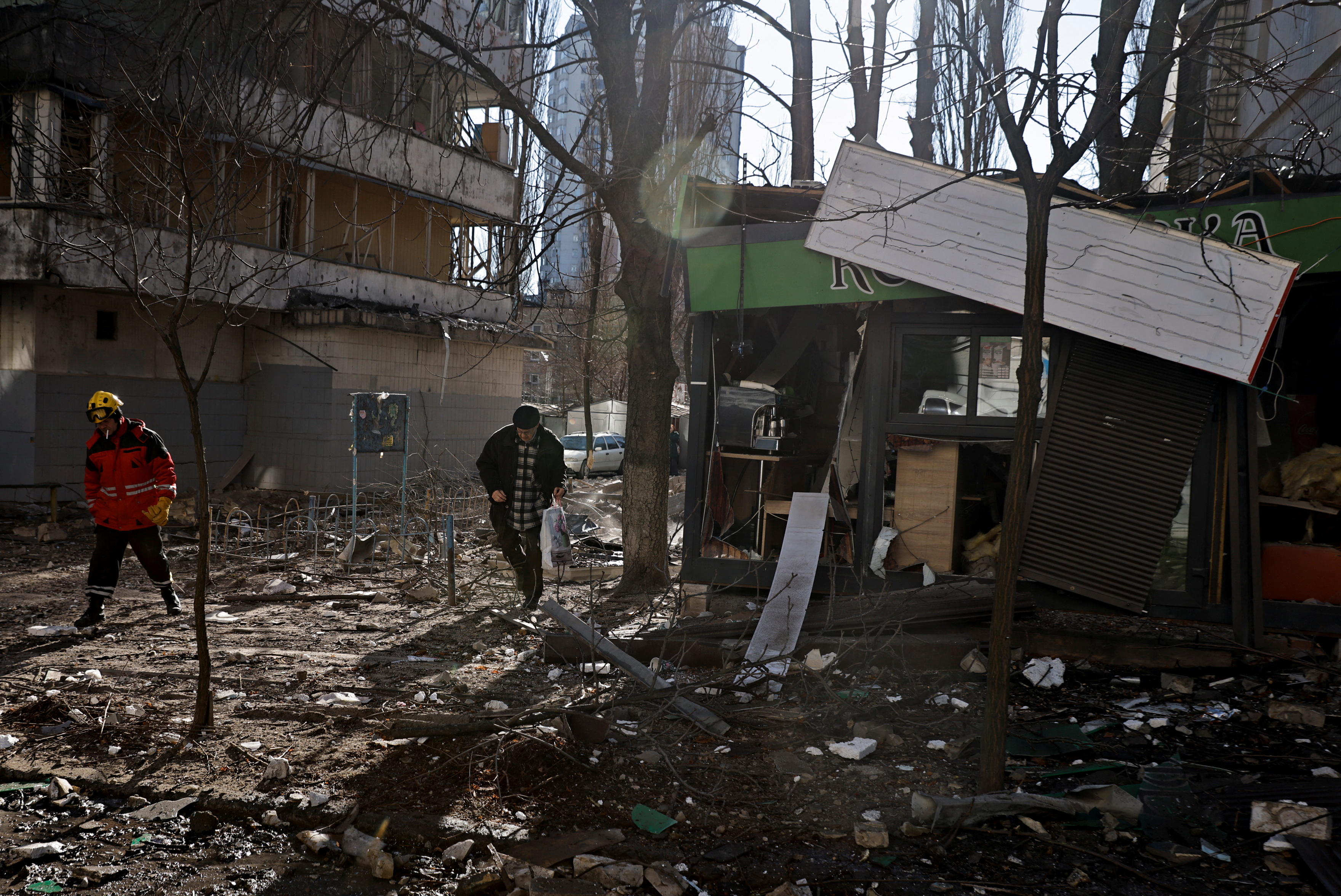 Resident walks through debris next to a building that was hit by shelling in Kyiv