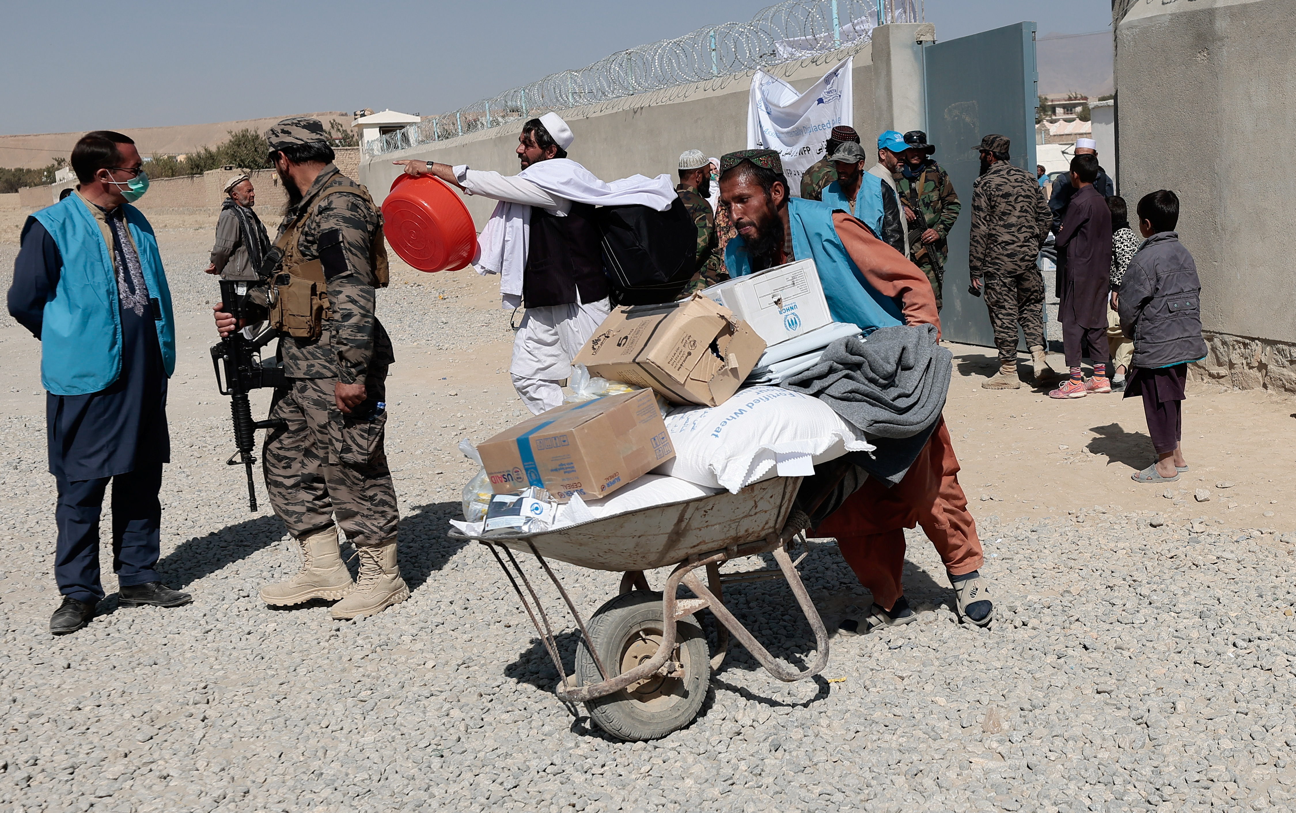 UNHCR worker pushes a wheelbarrow loaded with aid supplies for a displaced Afghan family outside the distribution center on the outskirts of Kabul