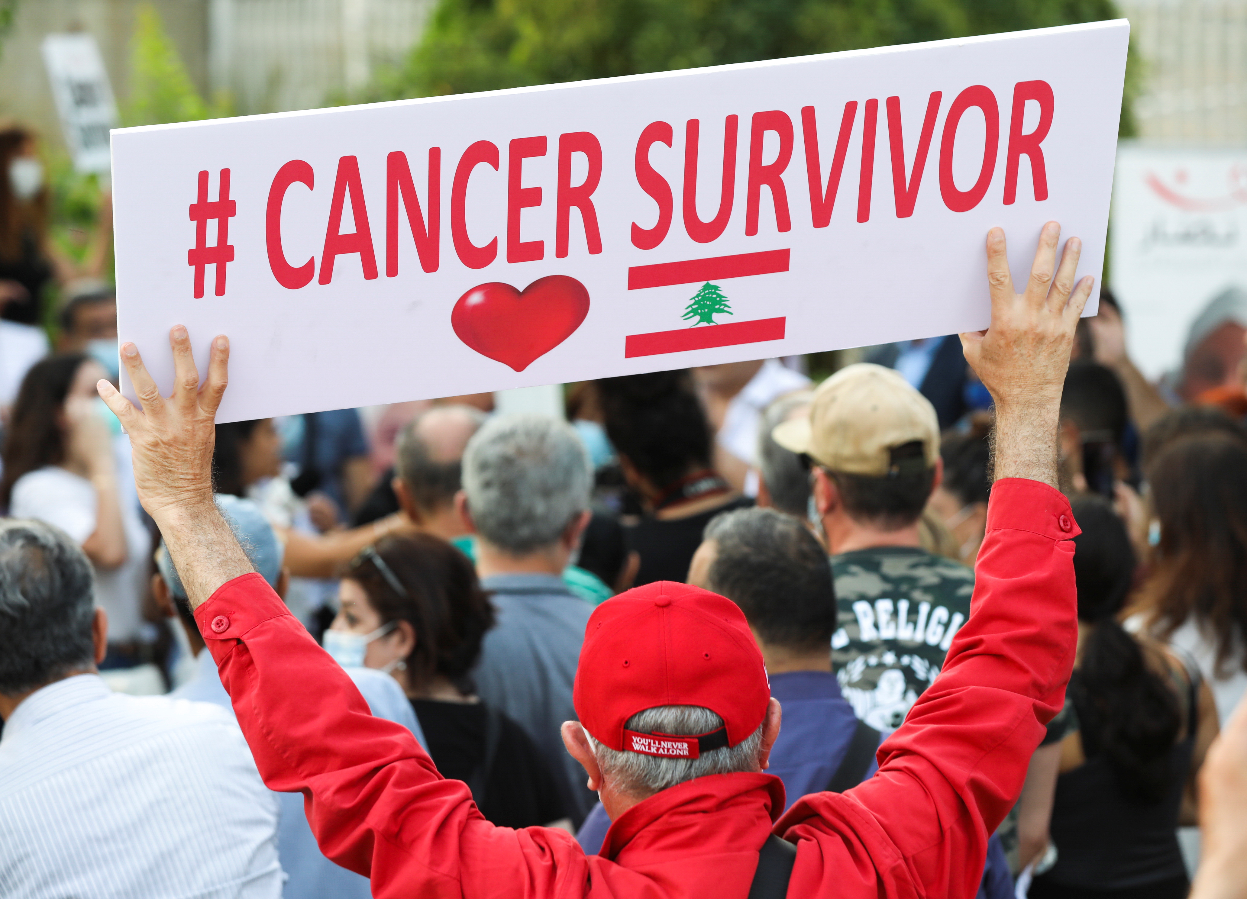 A man holds a sign during a sit-in demonstration as shortages of cancer medications spread, in front of the U.N. headquarters in Beirut