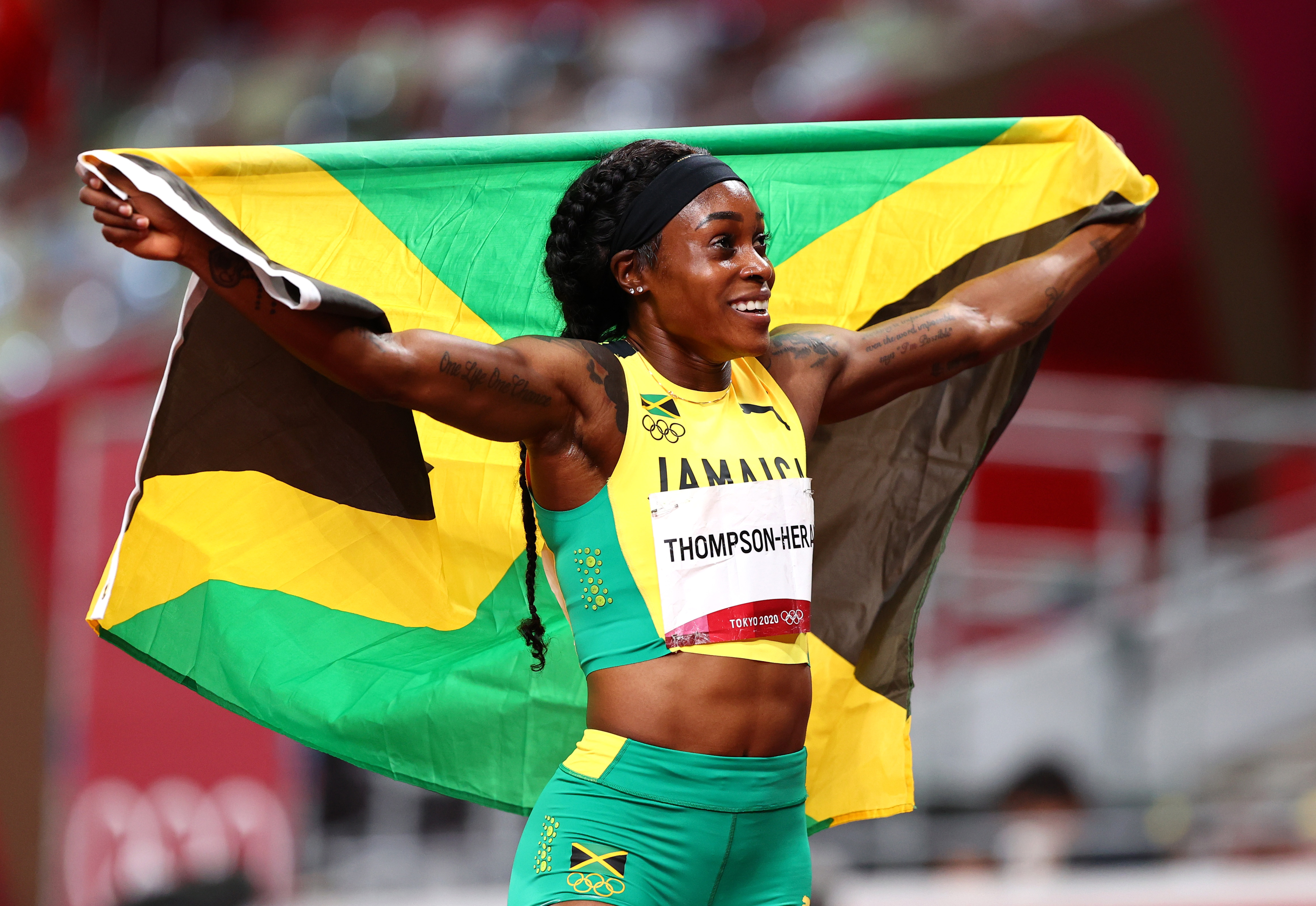 Tokyo 2020 Olympics - Athletics - Women's 200m - Final - Olympic Stadium, Tokyo, Japan - August 3, 2021. Elaine Thompson-Herah of Jamaica poses with her national flag after winning gold REUTERS/Lucy Nicholson
