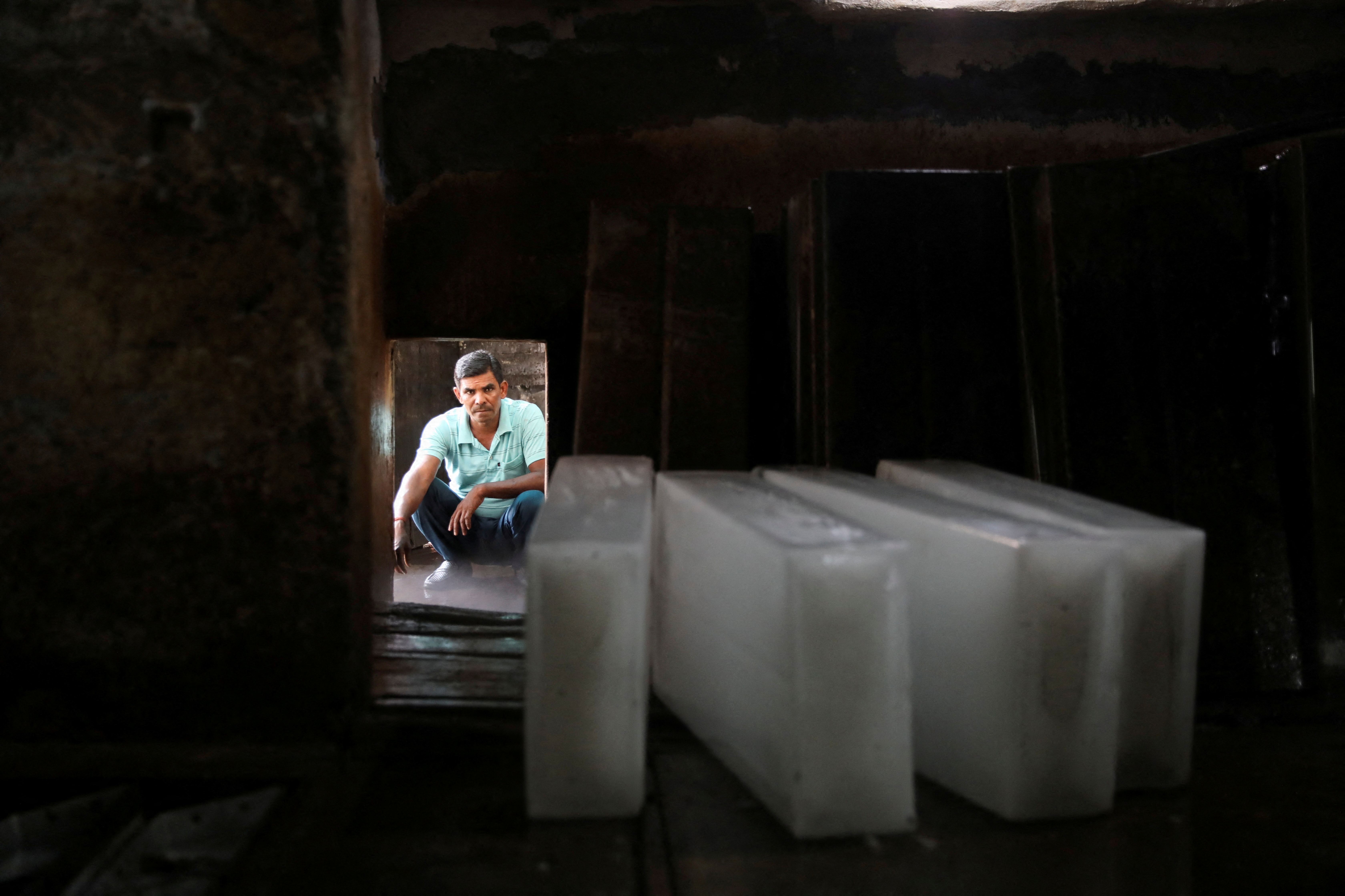 Worker waits to load ice blocks onto a truck, at an ice factory, on a hot summer day in New Delhi