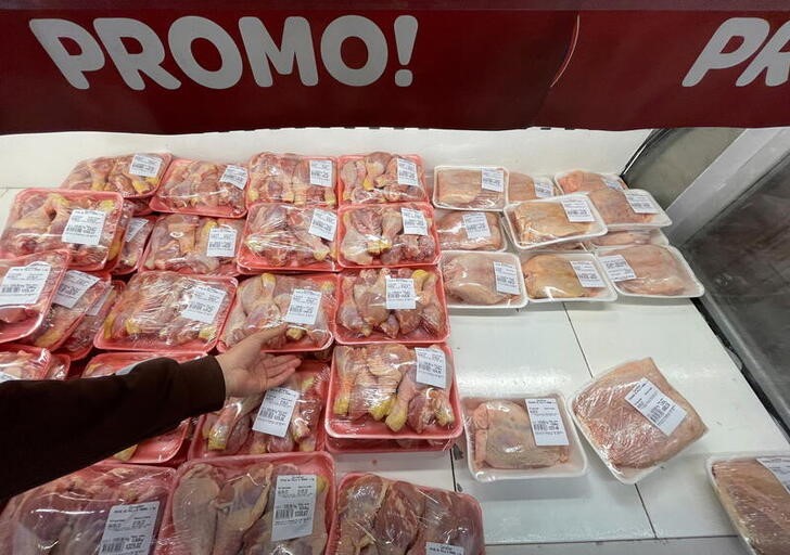 A man grabs chicken legs as he shops in a supermarket, in Buenos Aires