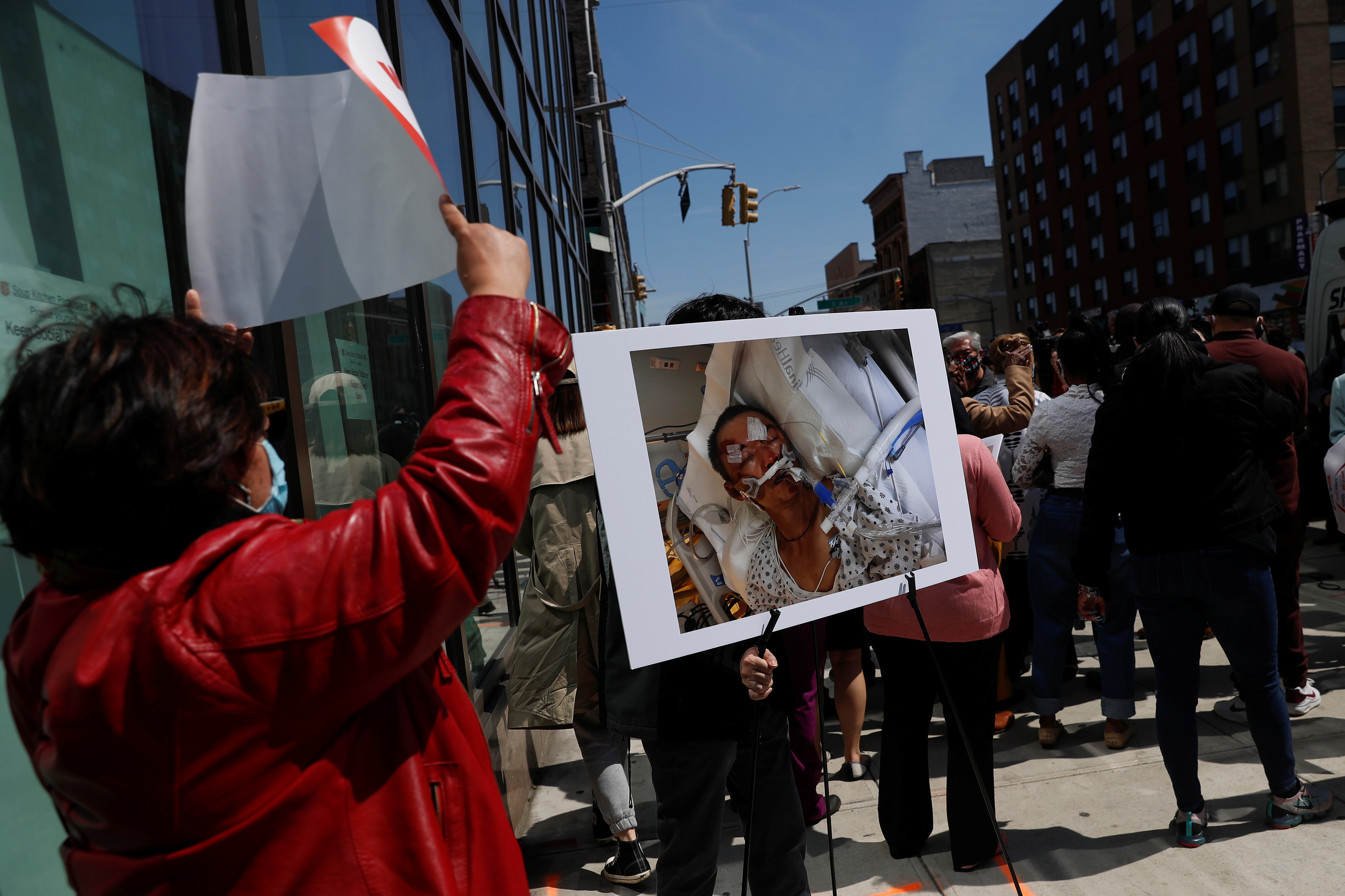 A man carries a photo of Yao Pan Ma in critical condition at a hospital, after being assaulted on April 23rd in the Harlem neighborhood of Manhattan, during a press conference in New York City