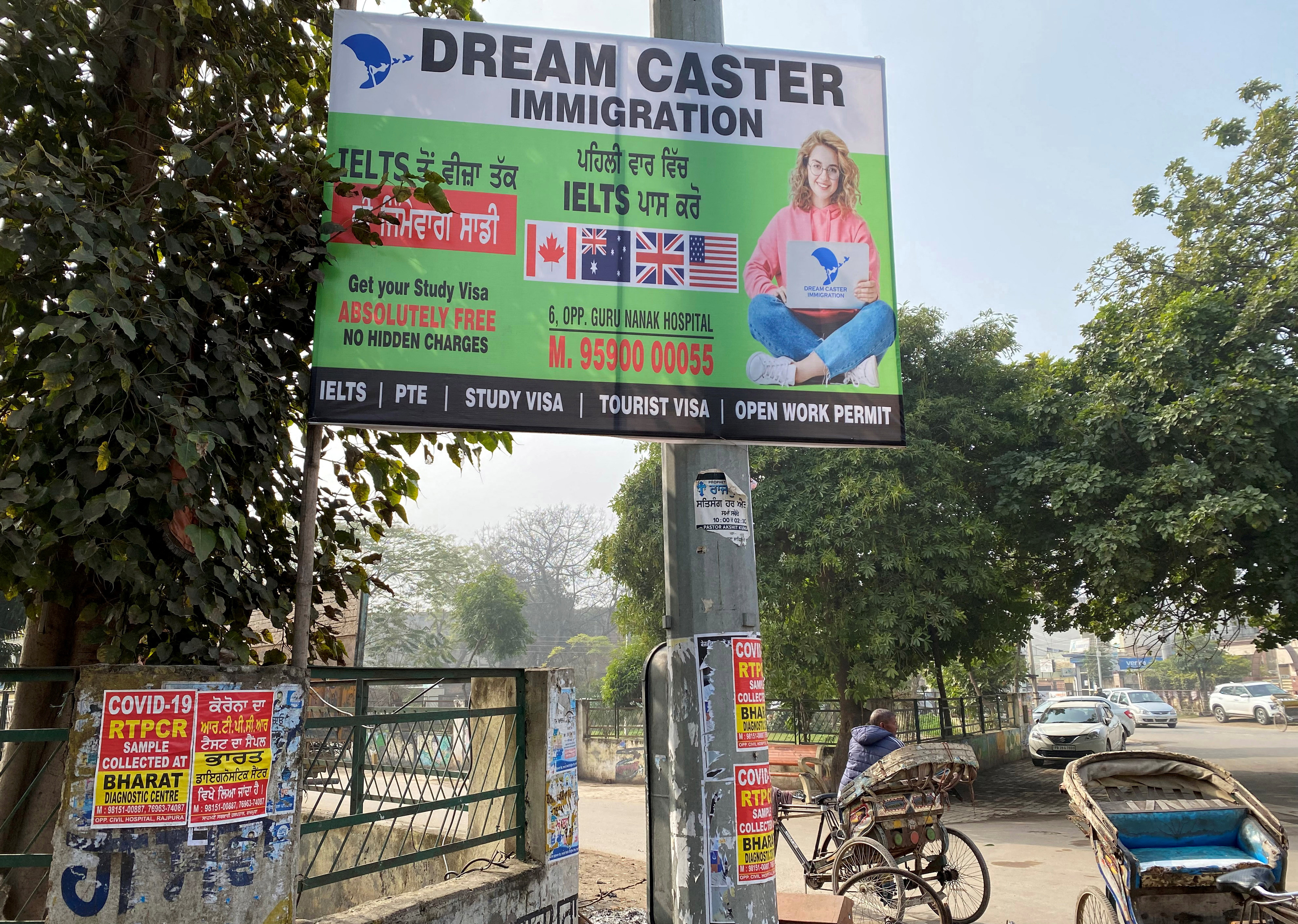 A poster of an immigration consulting agency hangs on an electricity pole in Rajpura