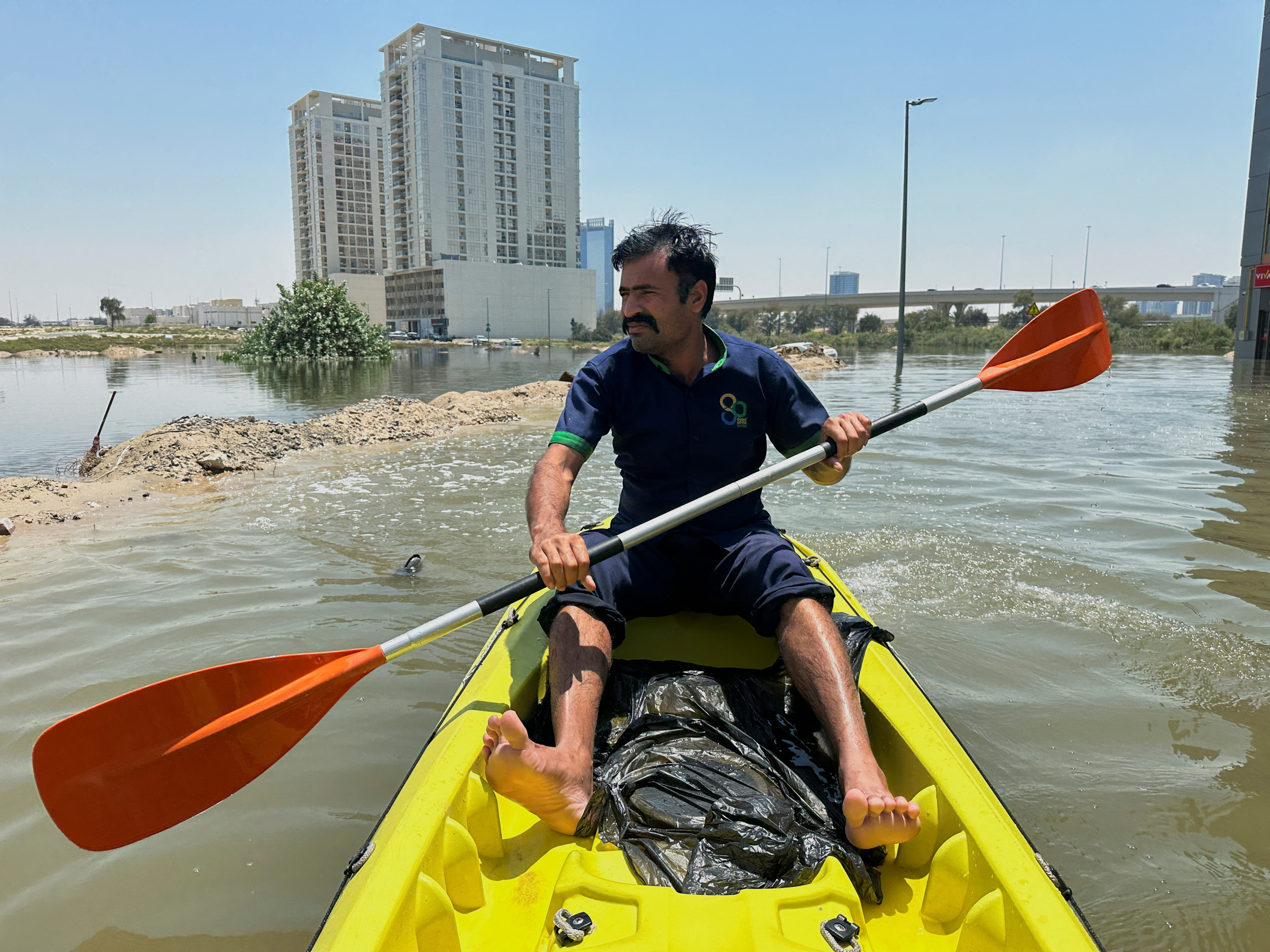 A volunteer uses a kayak during a rescue operation through a road flooded due to heavy rains in Dubai