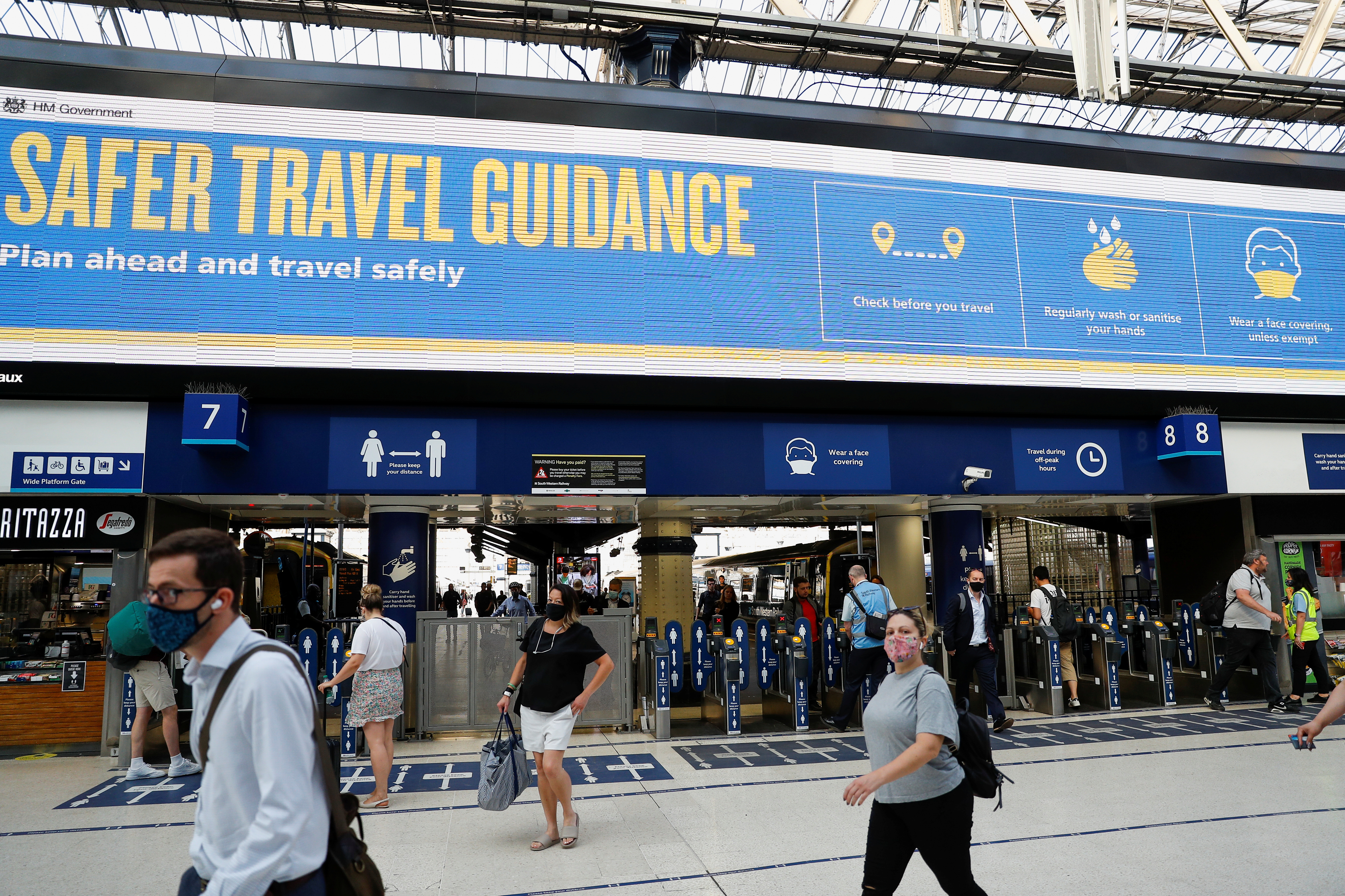 Commuters walk past a travel guidance sign, in London