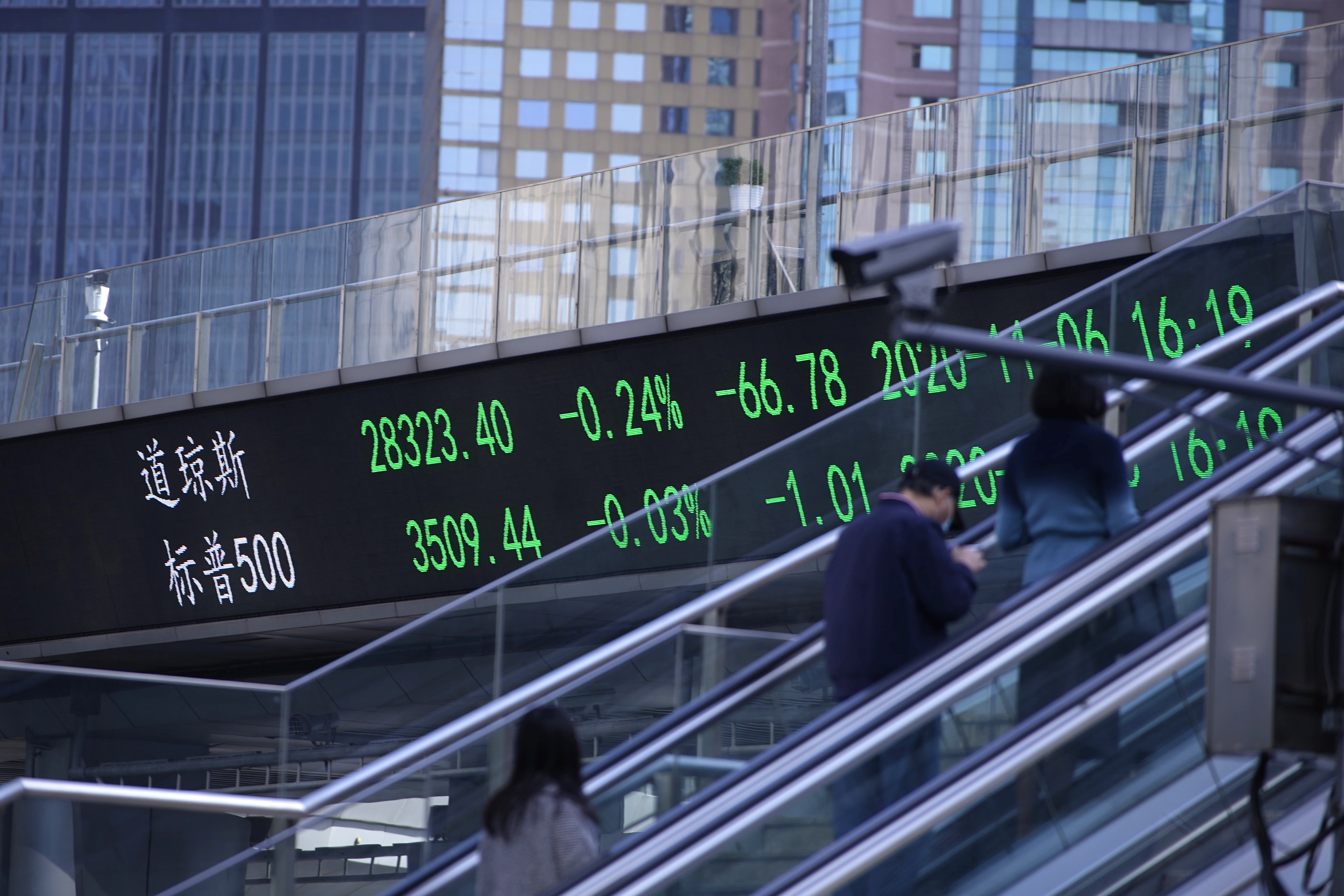  an electronic board showing Dow Jones and S&P 500 stock indexes, at the Lujiazui financial district in Shanghai