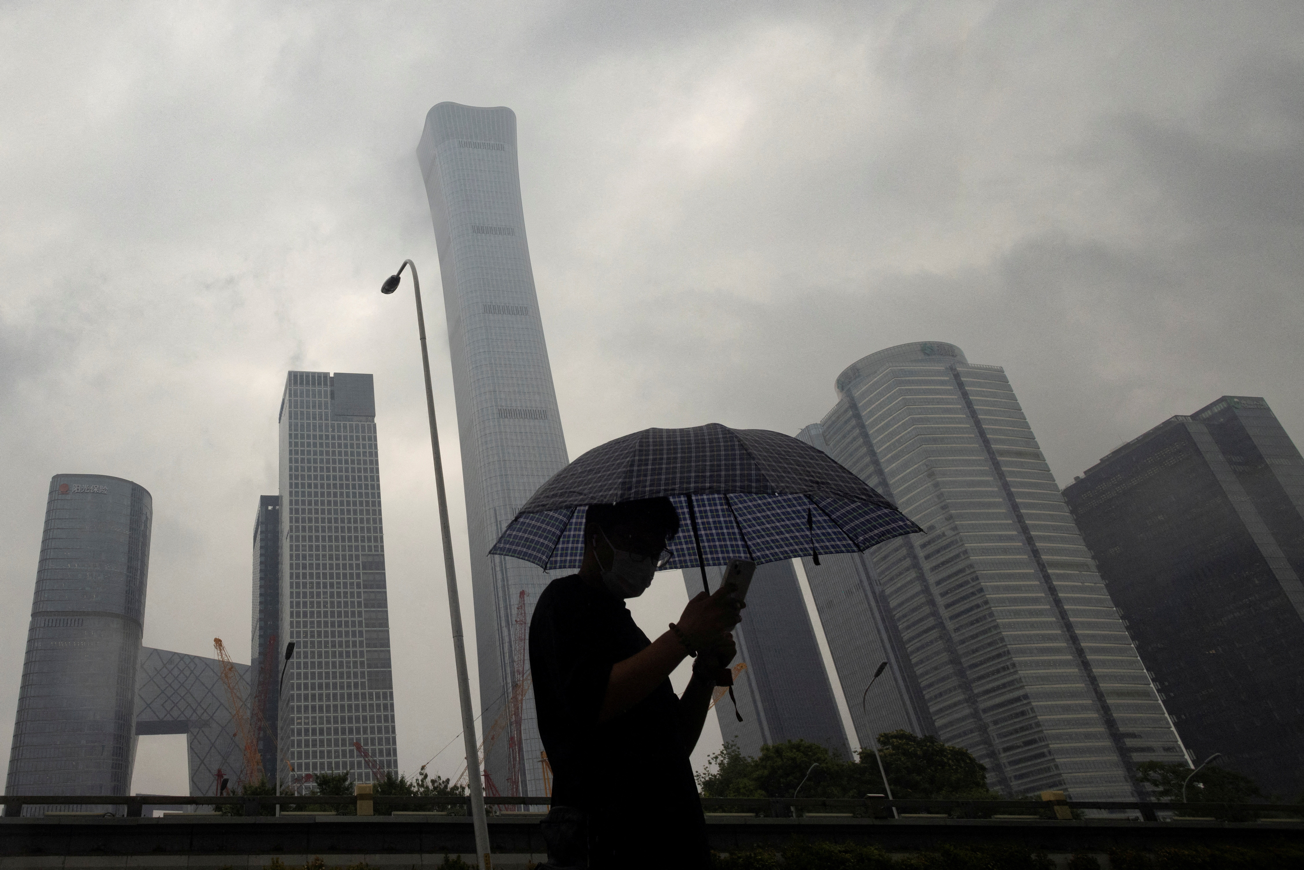 A man walks in the Central Business District on a rainy day, in Beijing