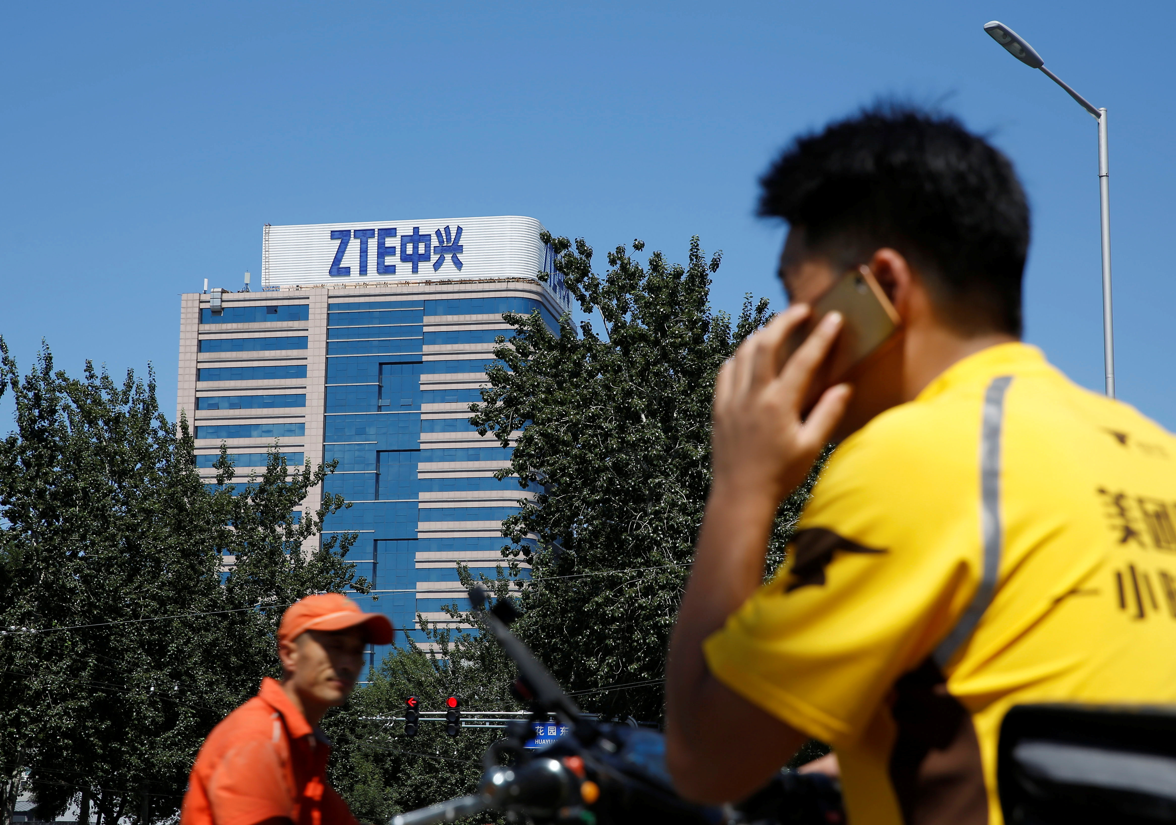 A delivery man uses a phone near a building of China's ZTE Corp in Beijing