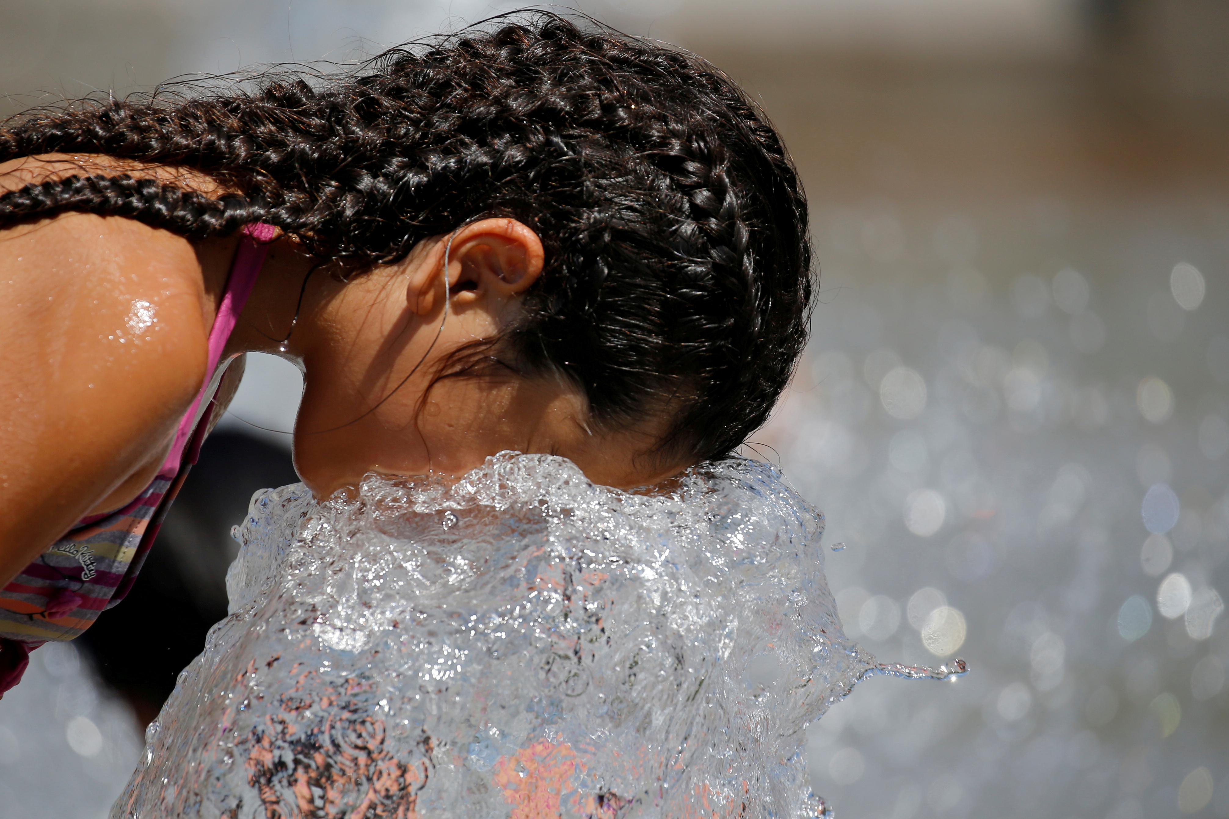 A child cools off in a fountain as a summer heatwave with high temperatures continues in Paris