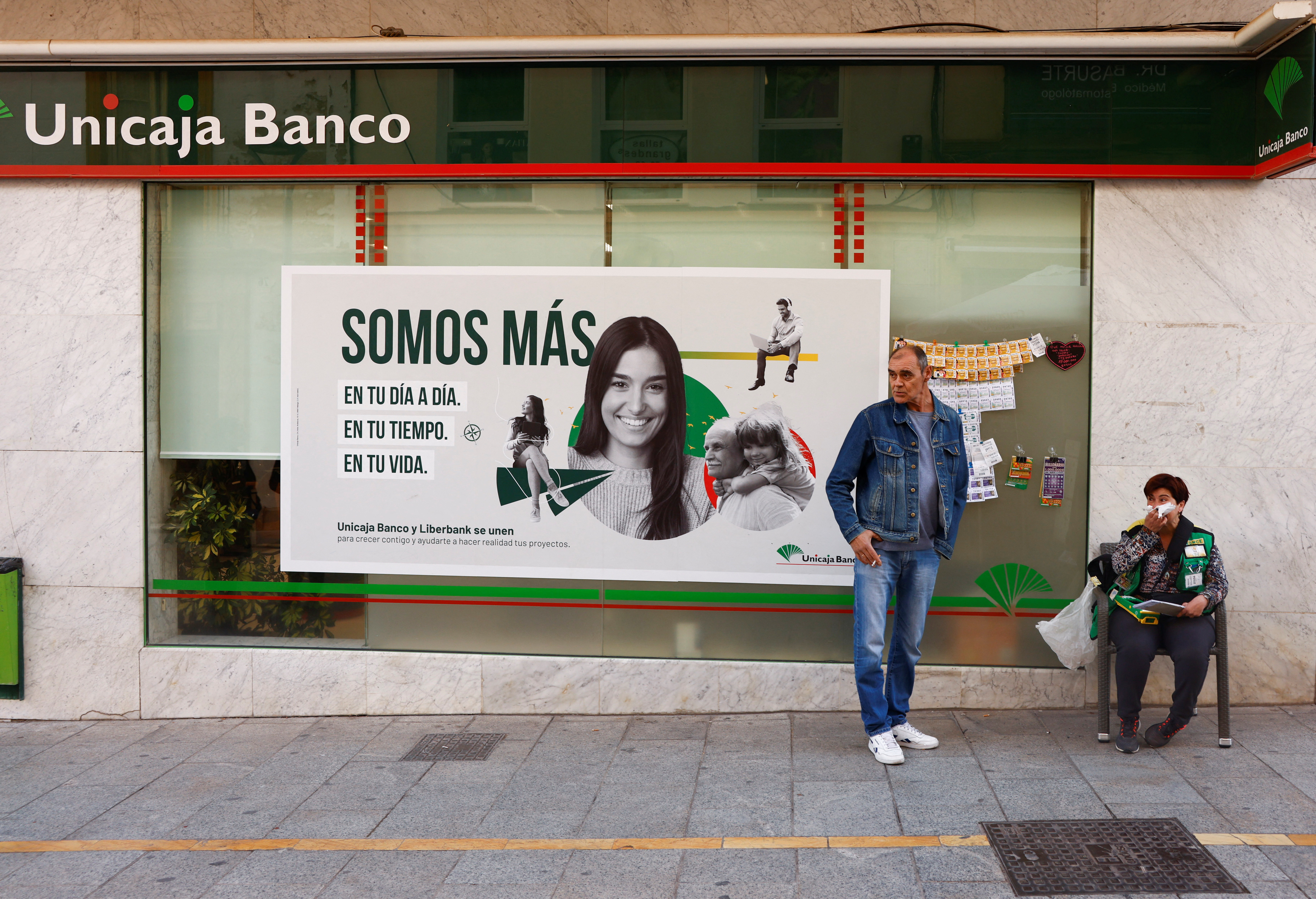 A lottery seller and a man wait outside of a Unicaja bank branch in Ronda