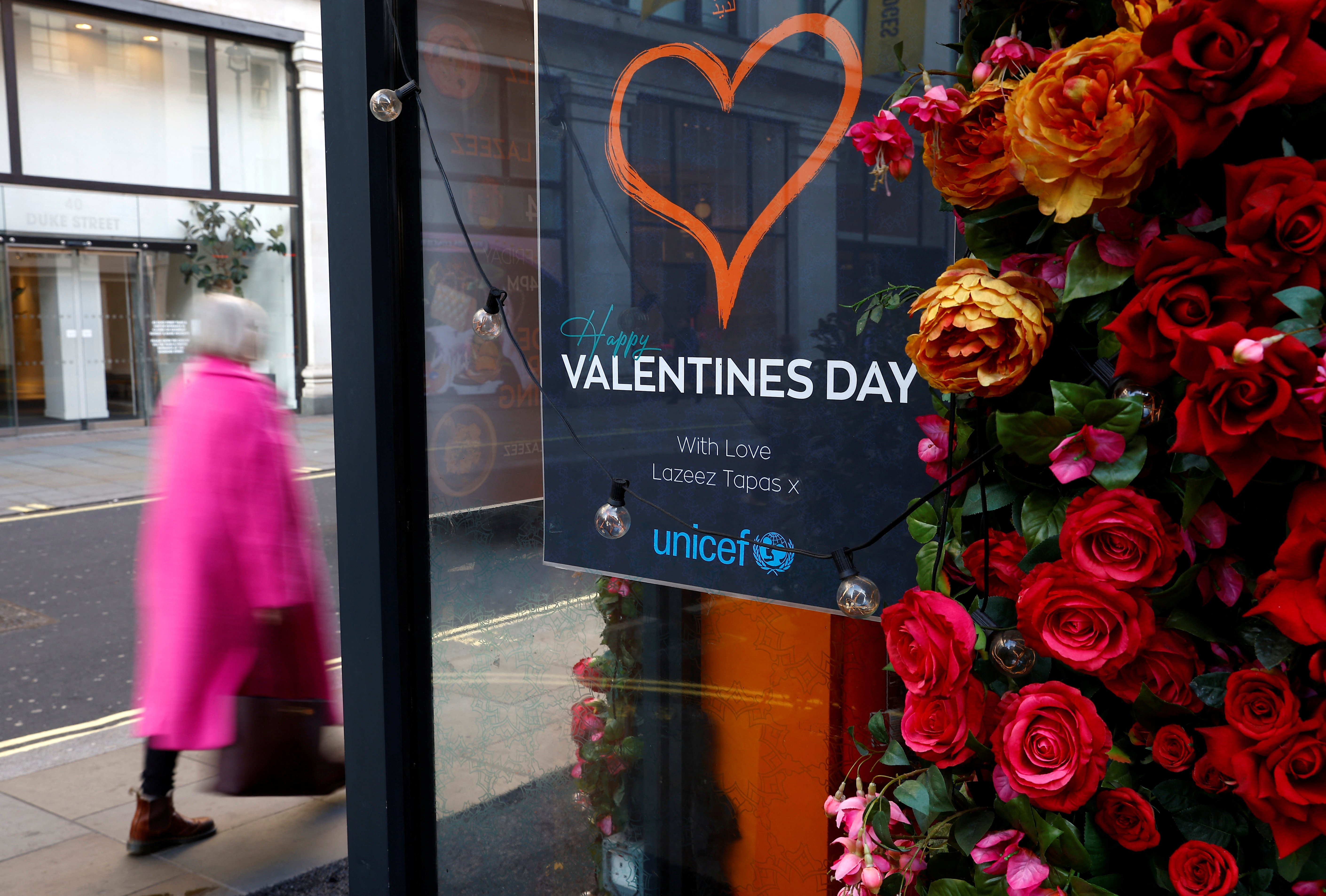 A woman walks past a Valentines Day sign in a restaurant in London