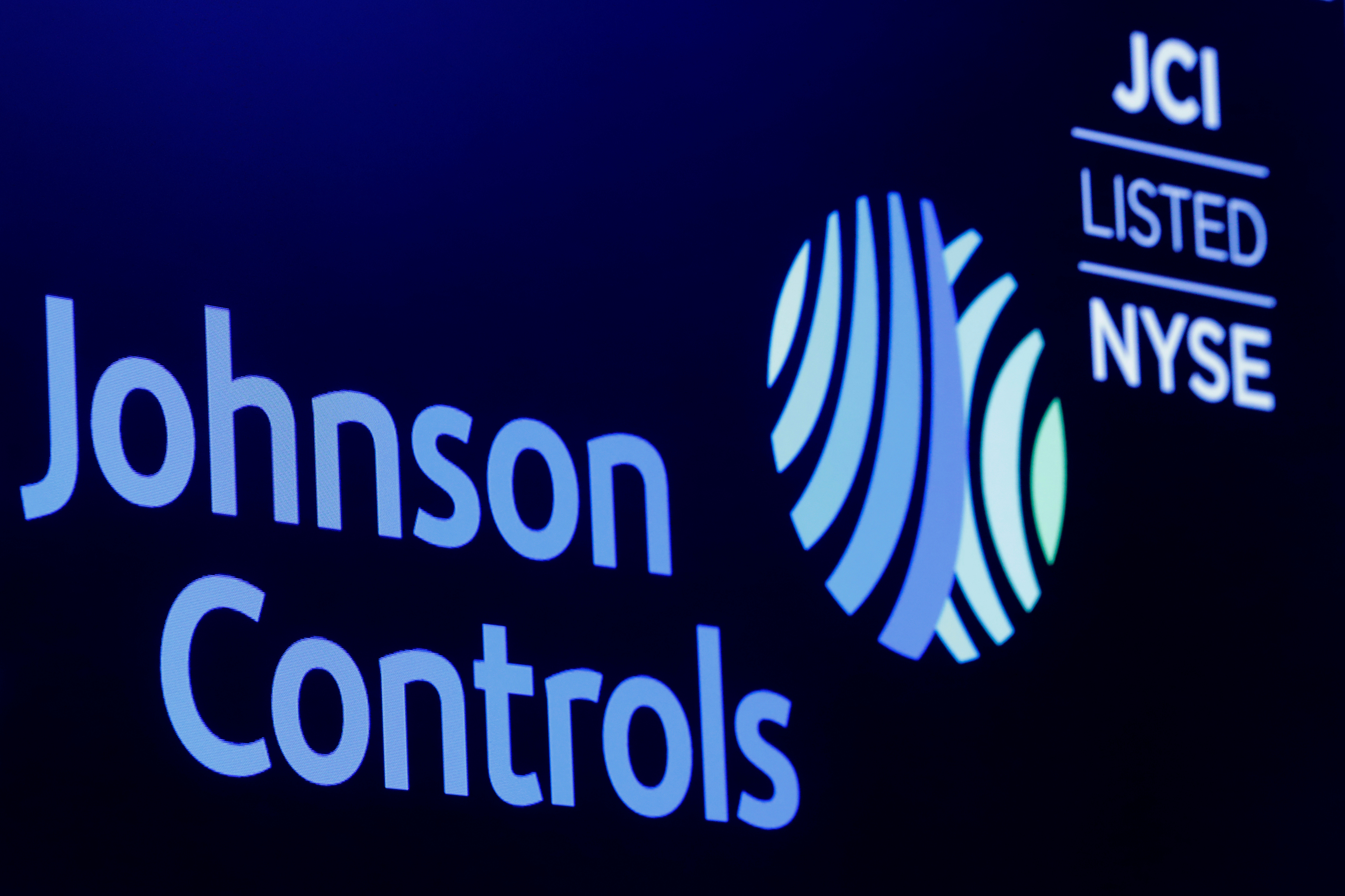 The logo and trading symbol for Johnson Controls International is displayed on a board on the floor of the NYSE in New York