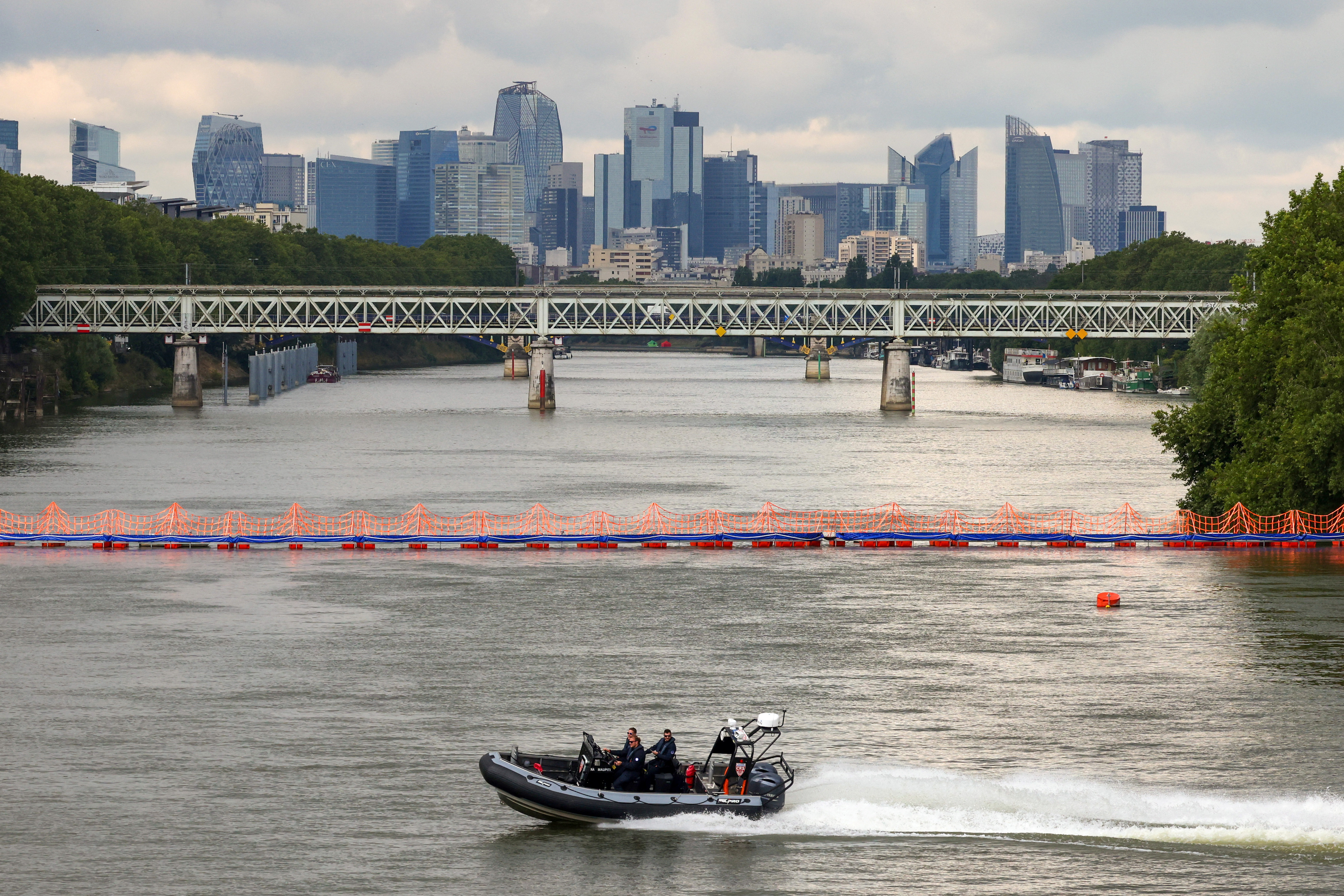 A CRS police speedboat patrols on the River Seine near a floating barrier