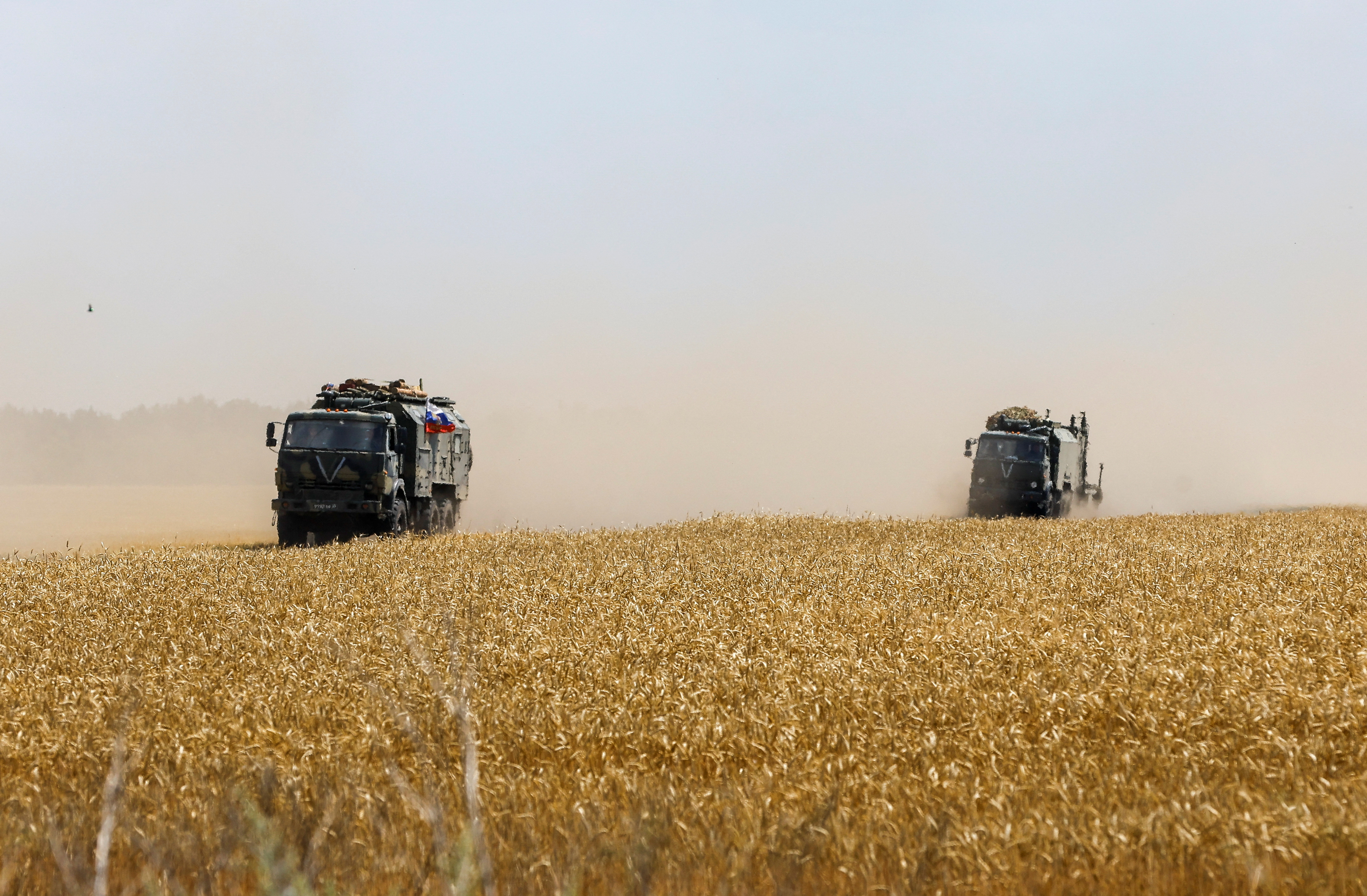 Russian army trucks drive across a wheat field in the course of Ukraine-Russia conflict near the settlement of Olenivka