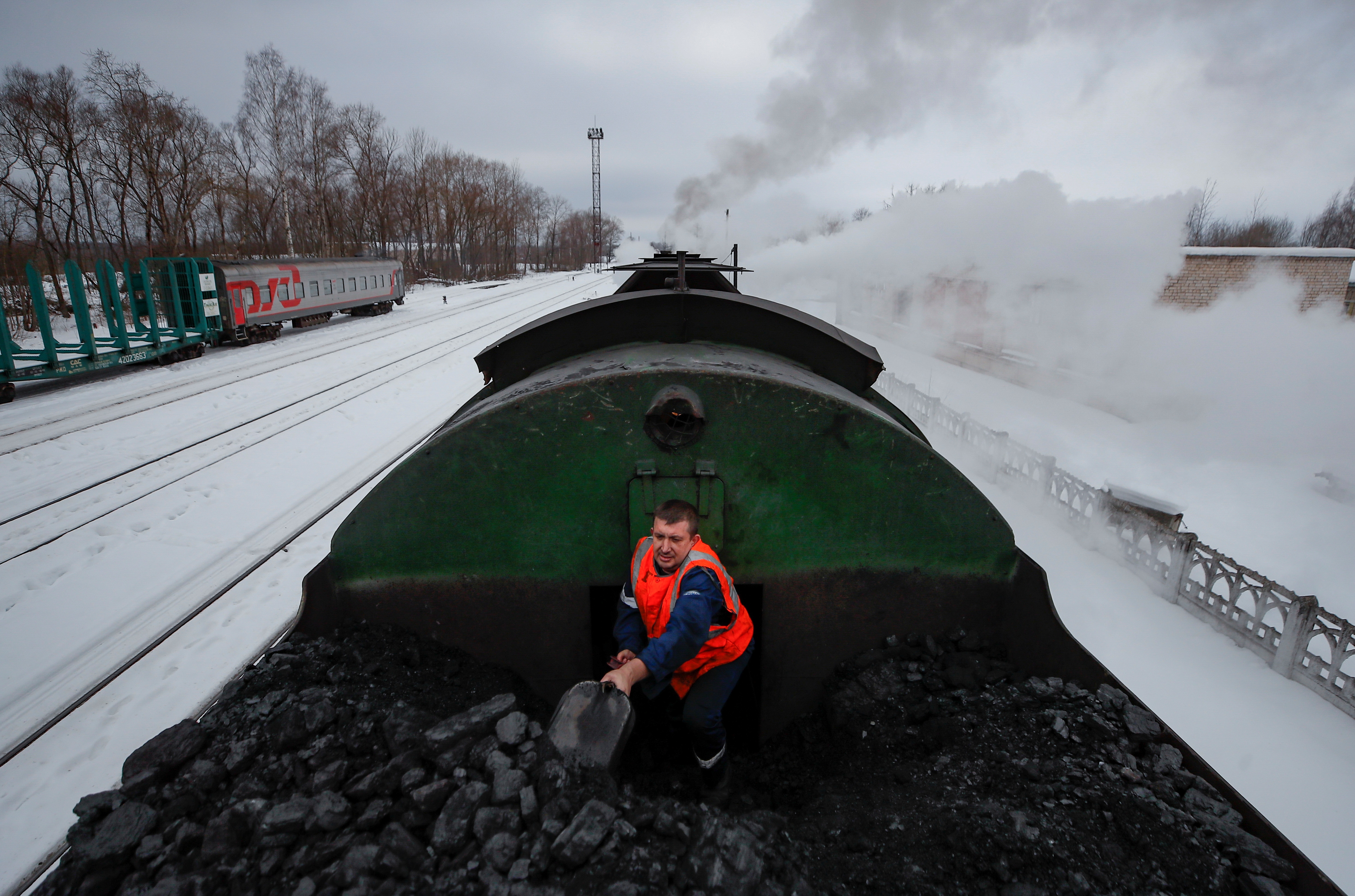 Mikhail Pestritsov, a member of locomotive crew, heaves coal in a tender of steam locomotive in Ostashkov