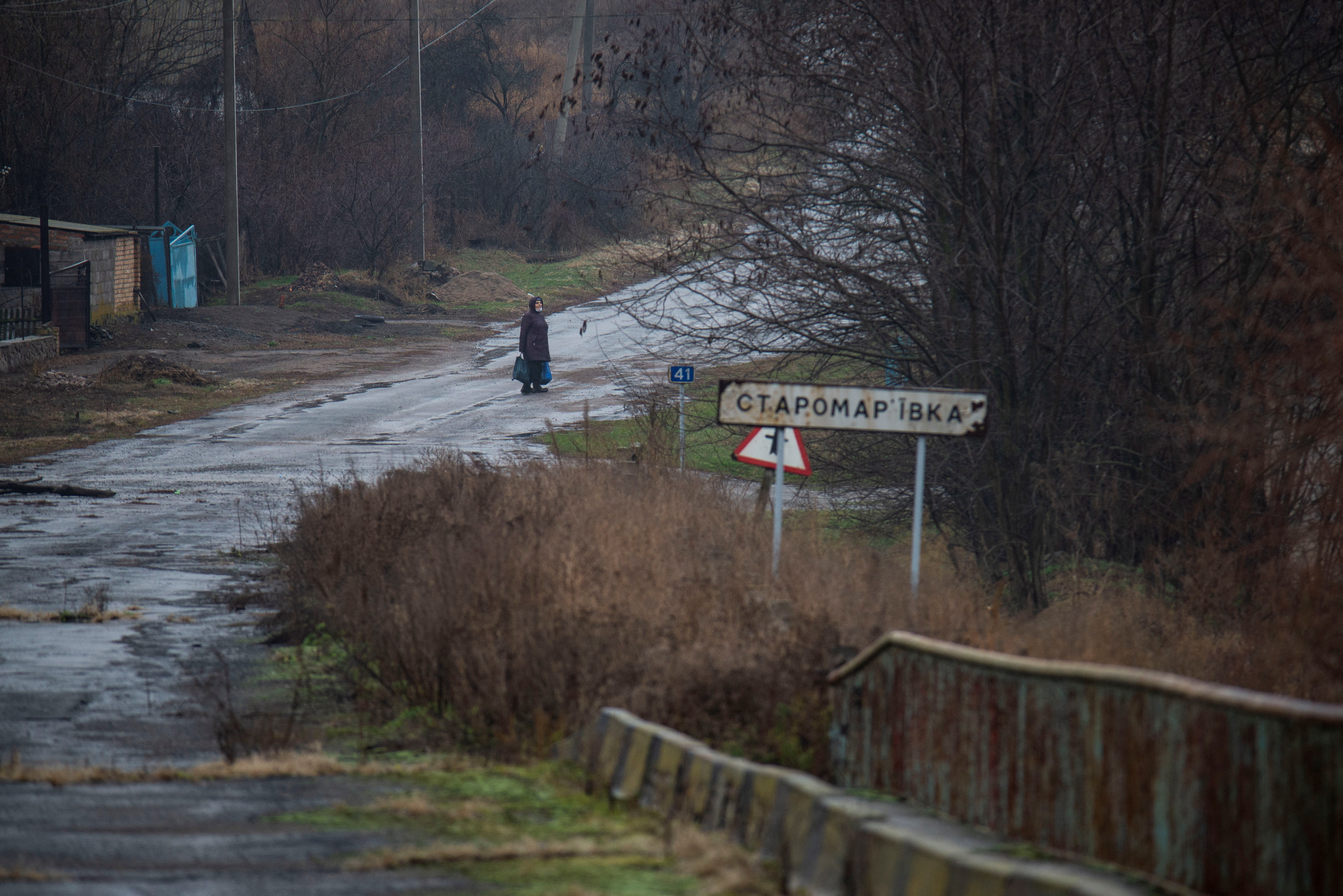 A woman stands on a road in the village of Staromarivka in Donetsk Region