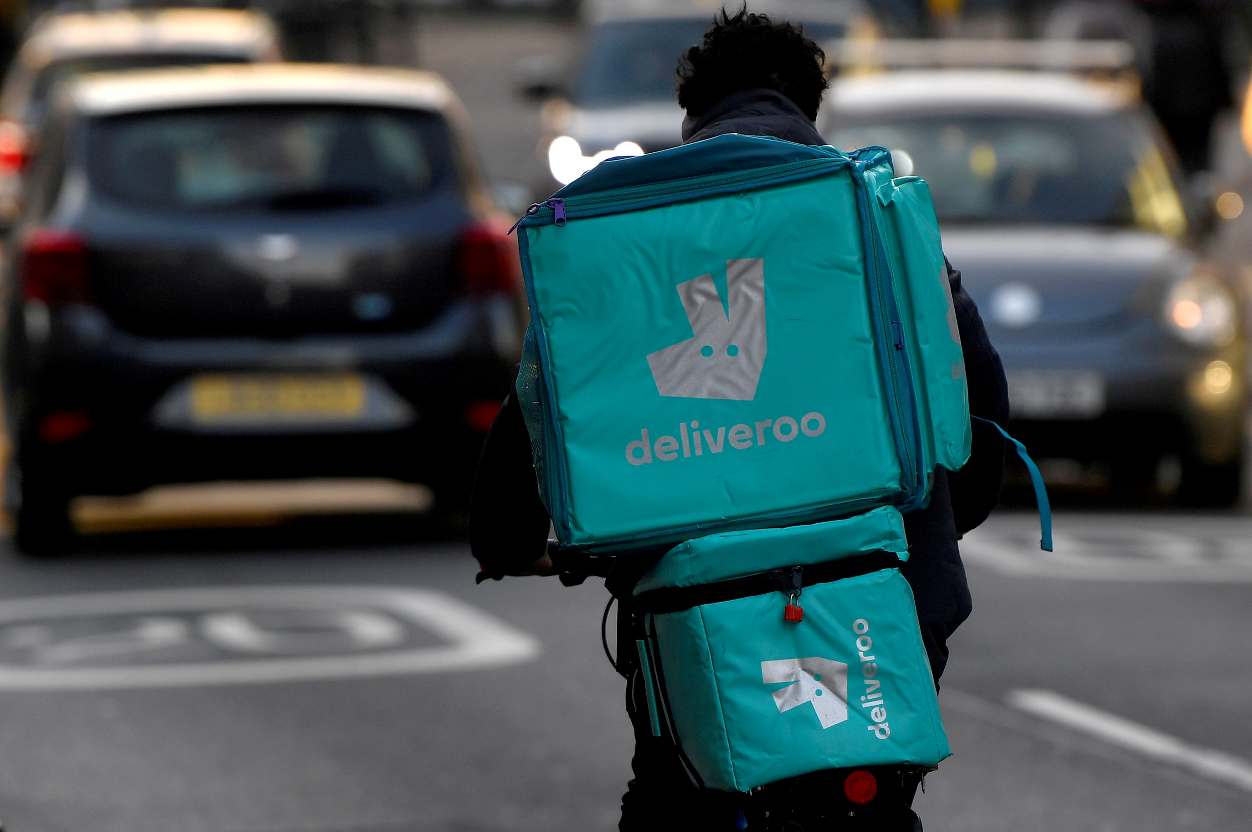 Deliveroo delivery rider cycles in London, Britain