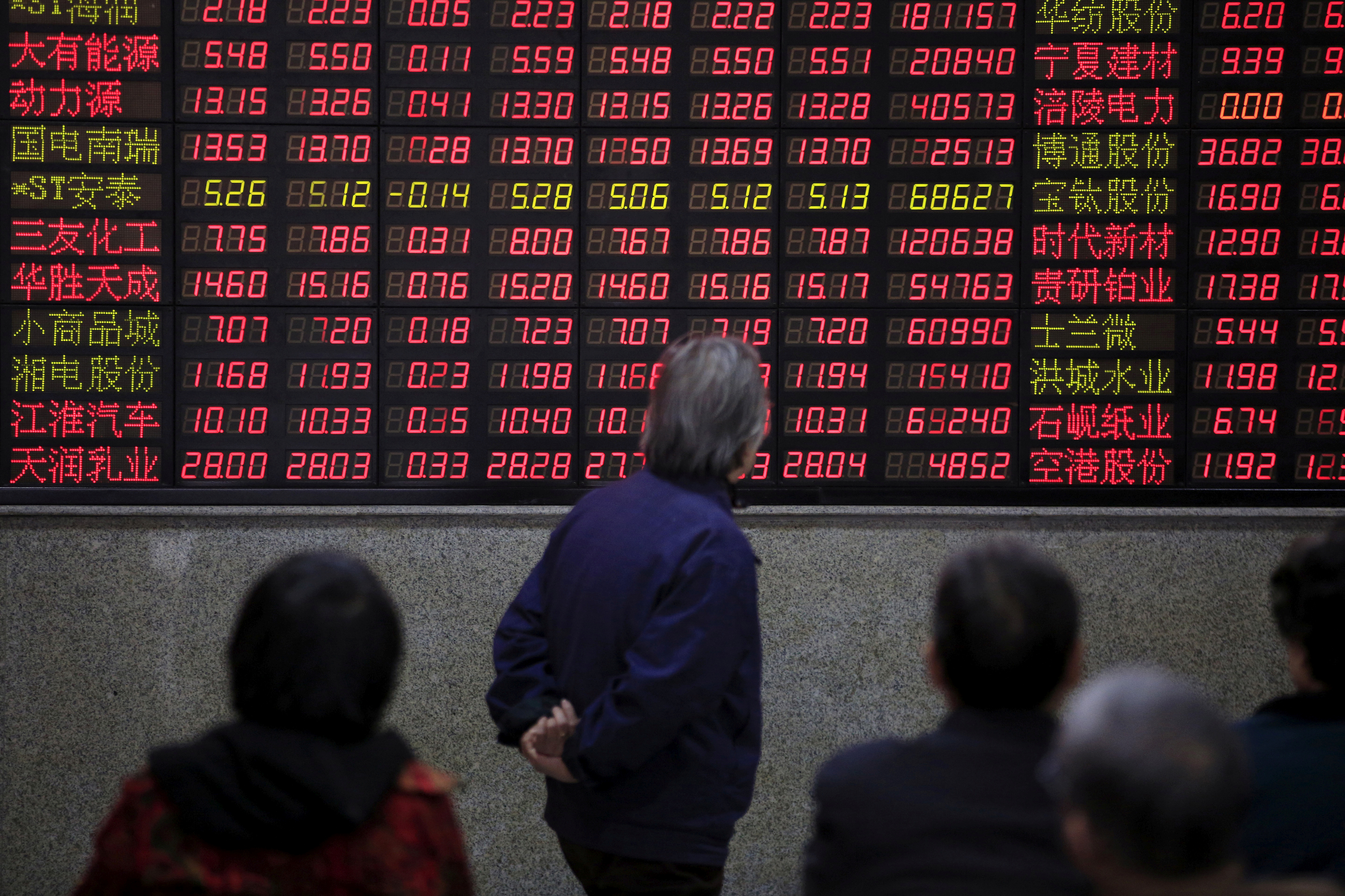 Investors look at an electronic board showing stock information at a brokerage house in Shanghai