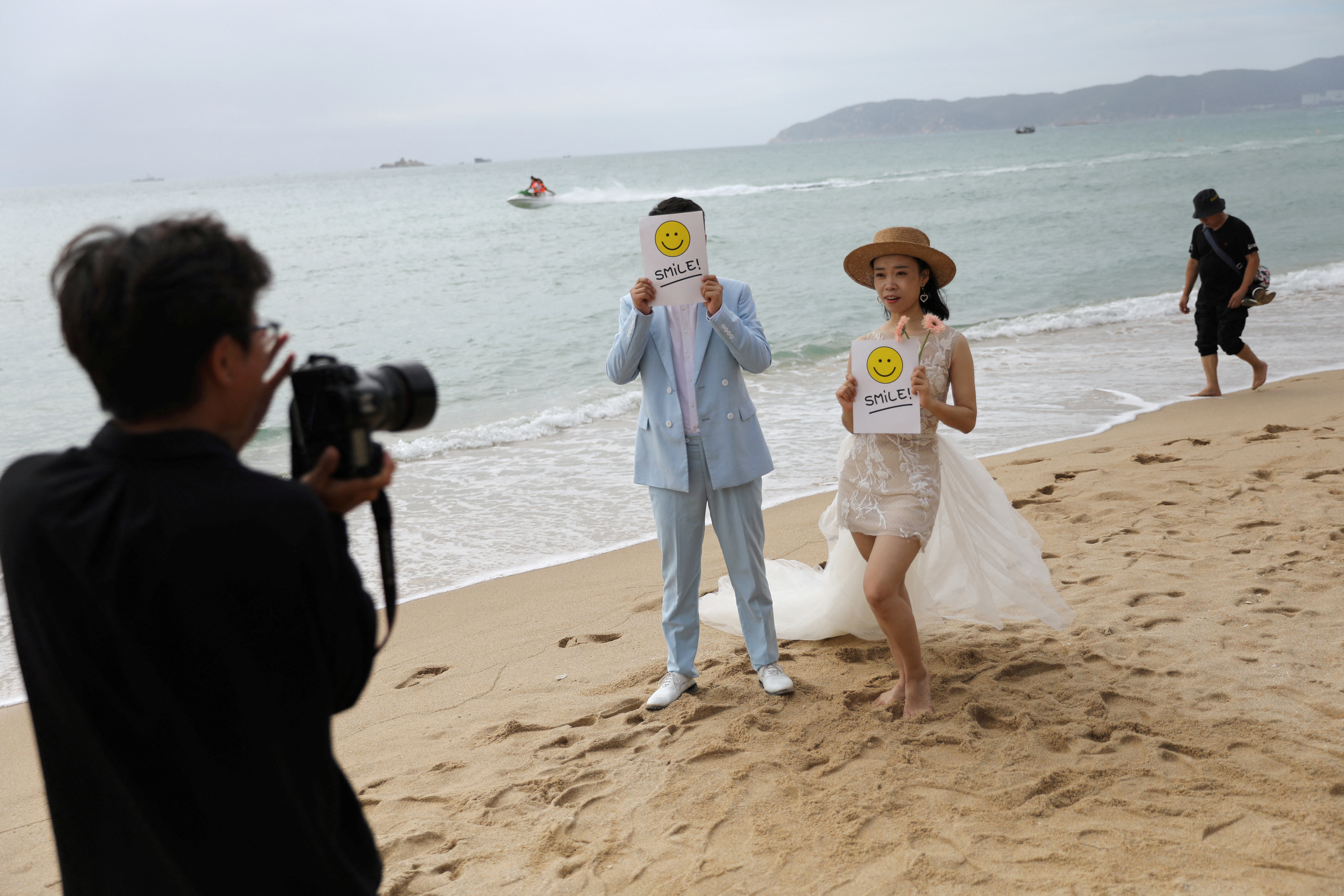 A couple poses for pictures during a wedding photoshoot session on Yalong Bay beach in Sanya