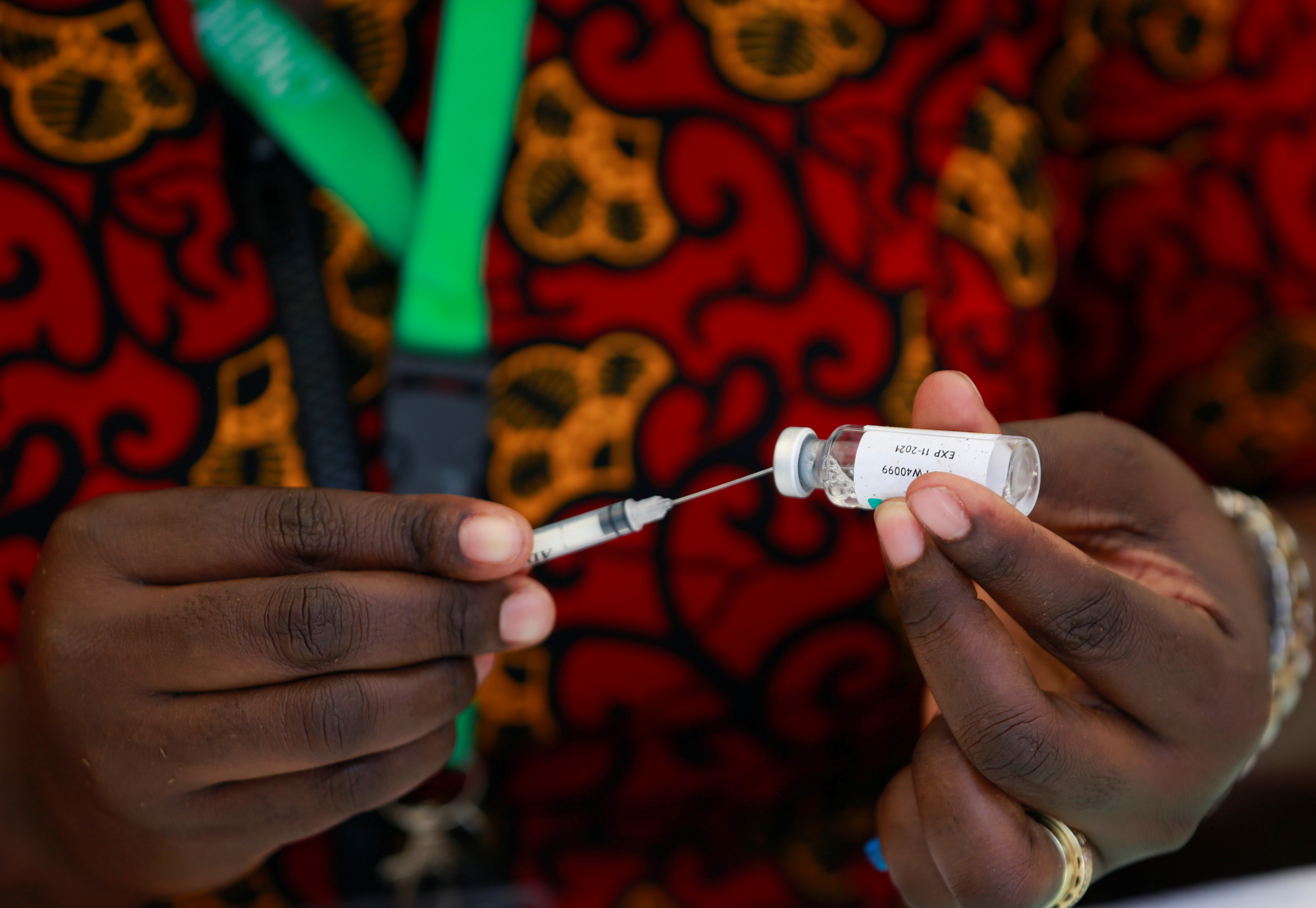 A health worker is takes a dose of the COVID-19 vaccine from a vial during the roll out of mass vaccination in Abuja