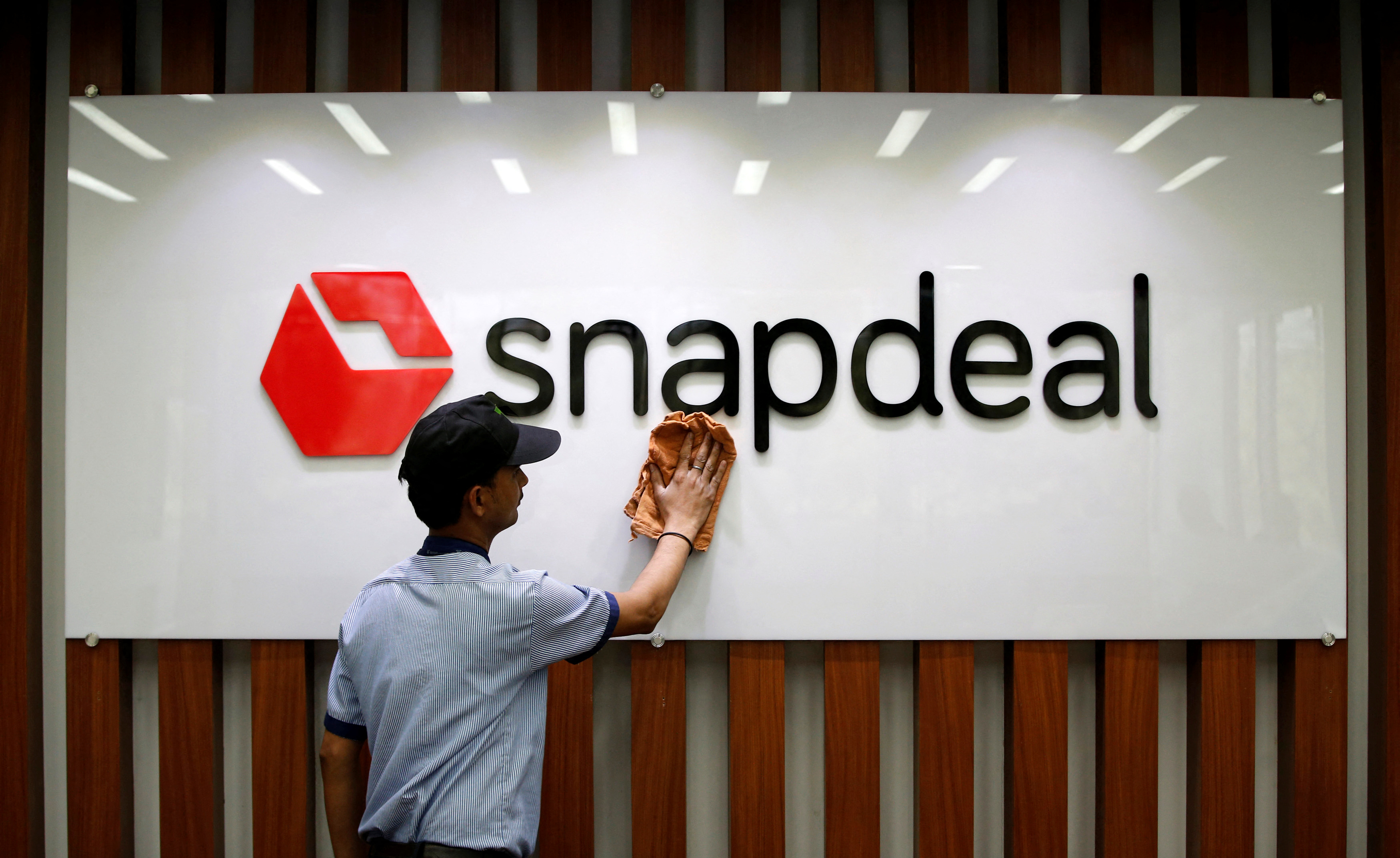 An employee cleans a Snapdeal logo at its headquarters in Gurugram