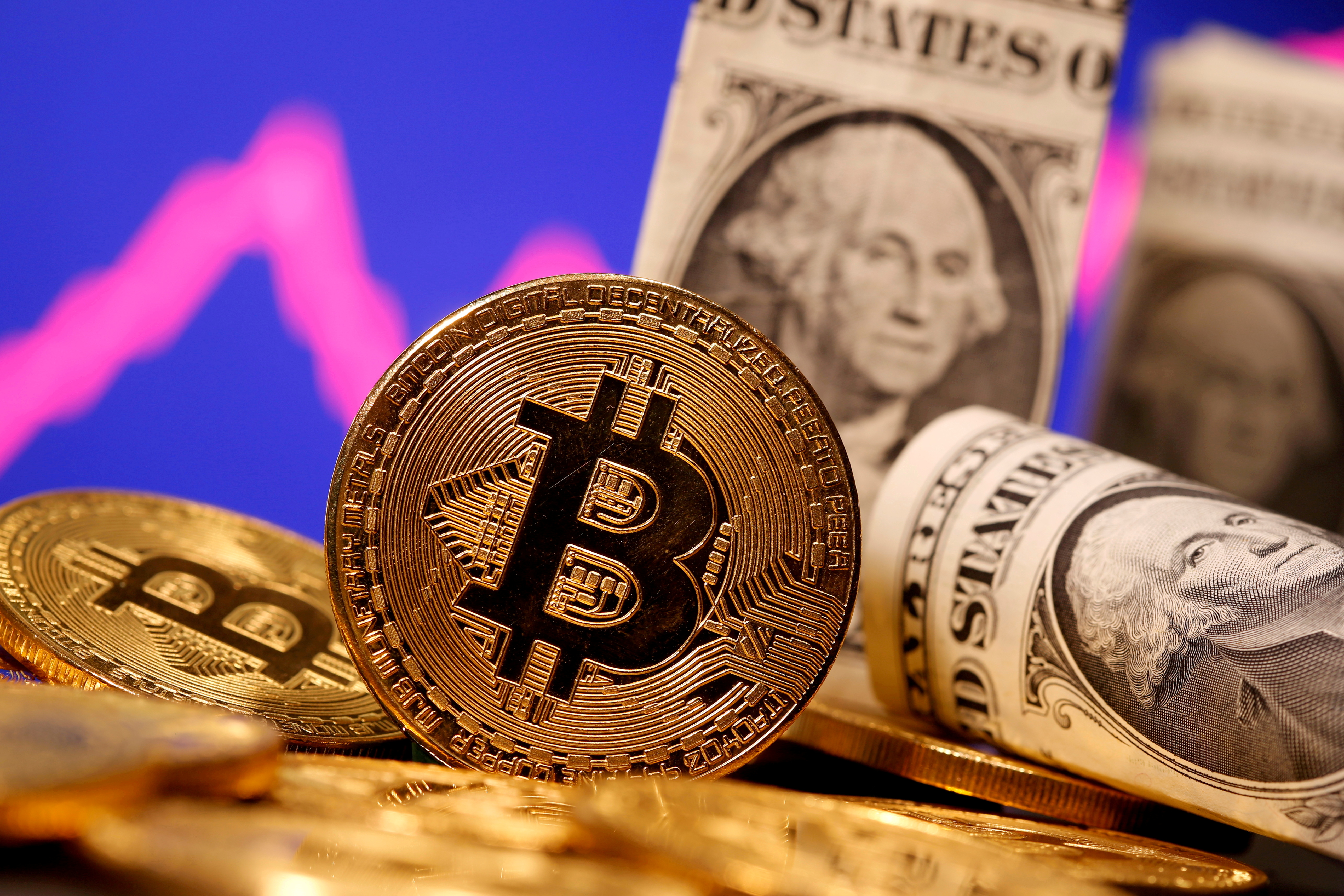 Hình ảnh đại diện của tiền ảo Bitcoin và tiền giấy Một Đô la Mỹ được nhìn thấy phía trước biểu đồ chứng khoán trong hình minh họa này được chụp vào ngày 8 tháng 1 năm 2021. REUTERS / Dado Ruvic / File Photo