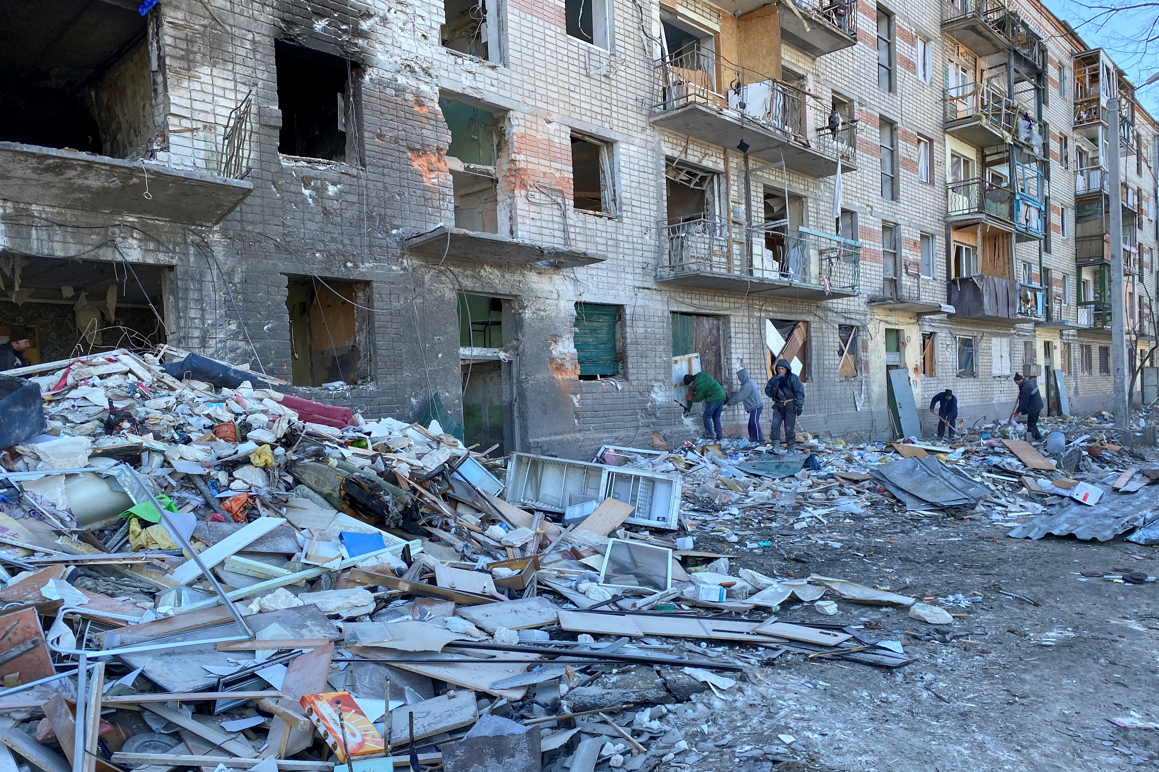Municipal workers and volunteers remove debris of a damaged residential building in Kharkiv