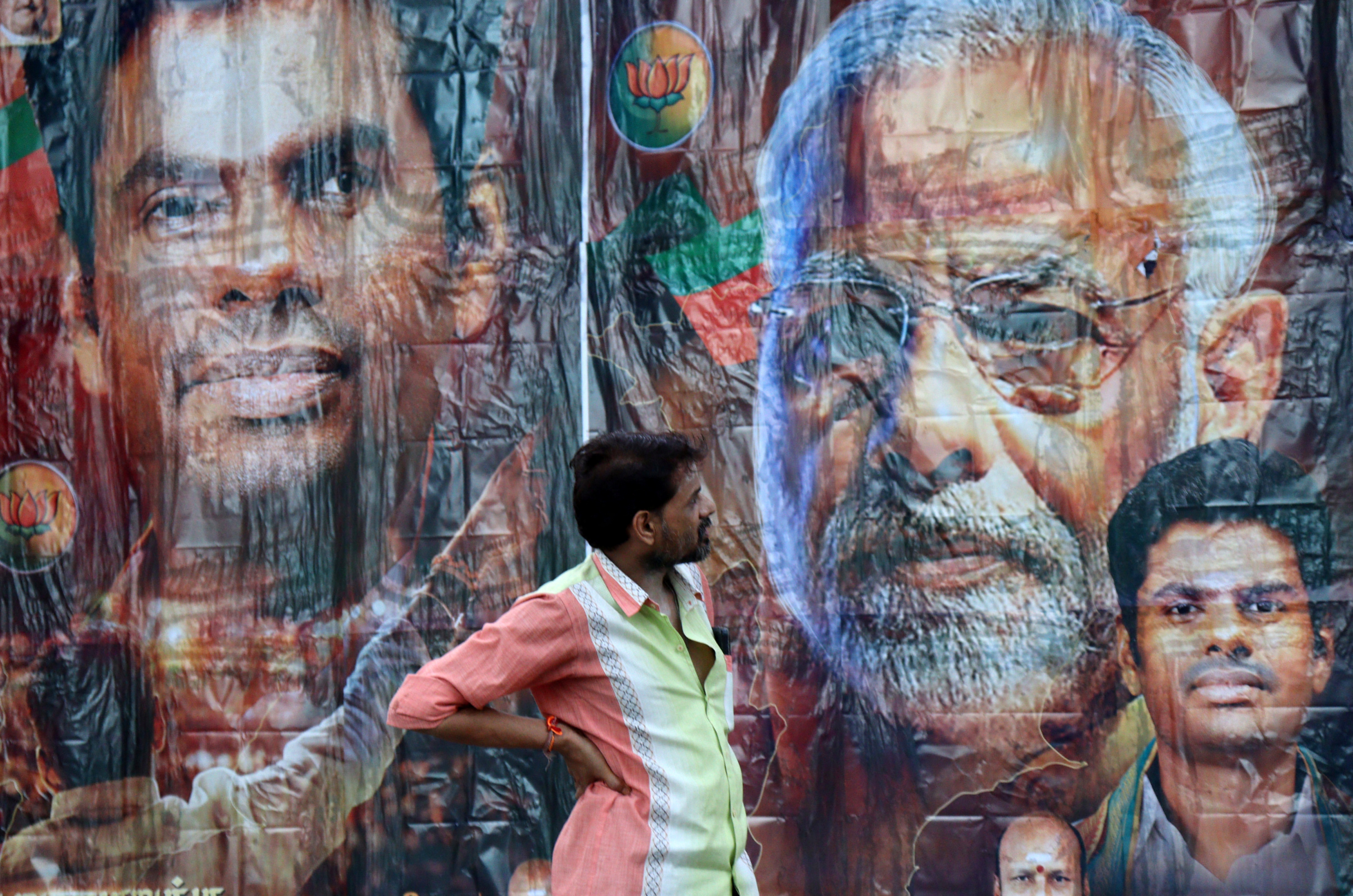 A man stands in front of a poster featuring PM Modi and Bharatiya Janata Party election candidate Annamalai, outside its party office in Chennai