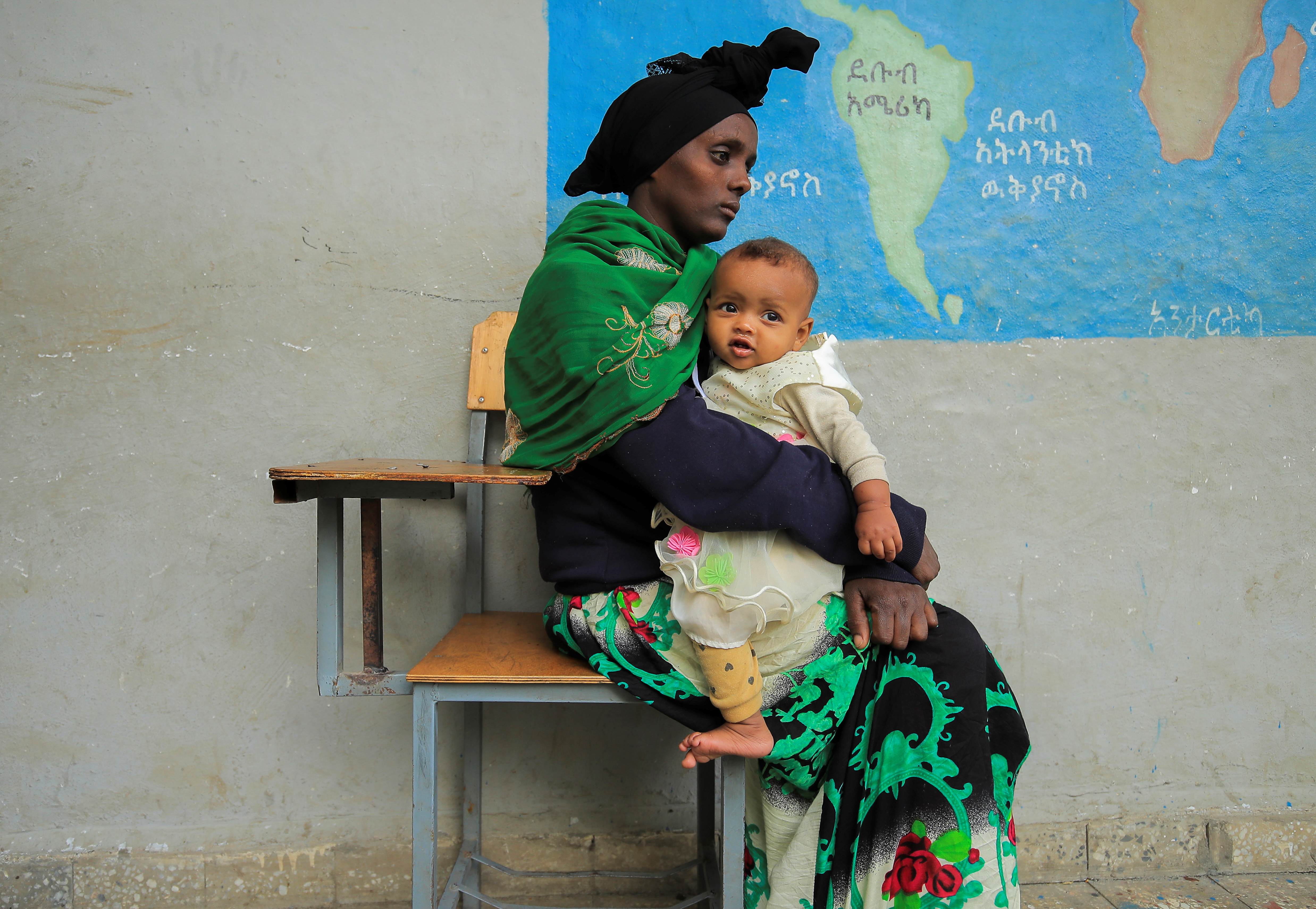 Habtam Akele, 27, carries her nine-months-old daughter, Kalkidan Alemu as they sit at a school makeshift camp for internally displaced people due to the fighting between the Ethiopian National Defense Force (ENDF) and the Tigray People's Liberation Front (TPLF) forces, in Dessie town, Amhara Region, Ethiopia, October 9, 2021. REUTERS/Tiksa Negeri