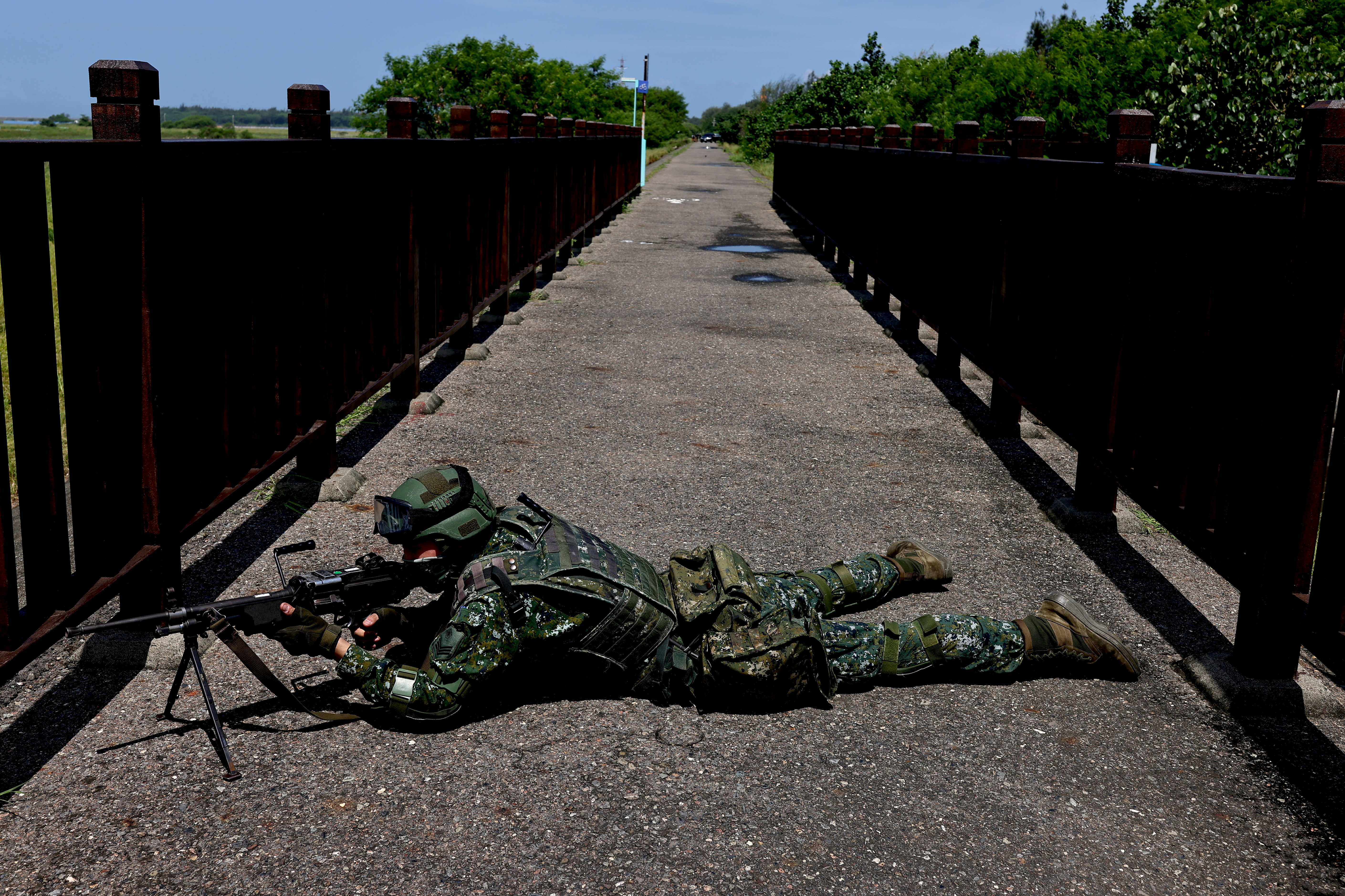 A soldier lies with a rifle on a bike lane by a beach during the annual Han Kuang military drill in Tainan