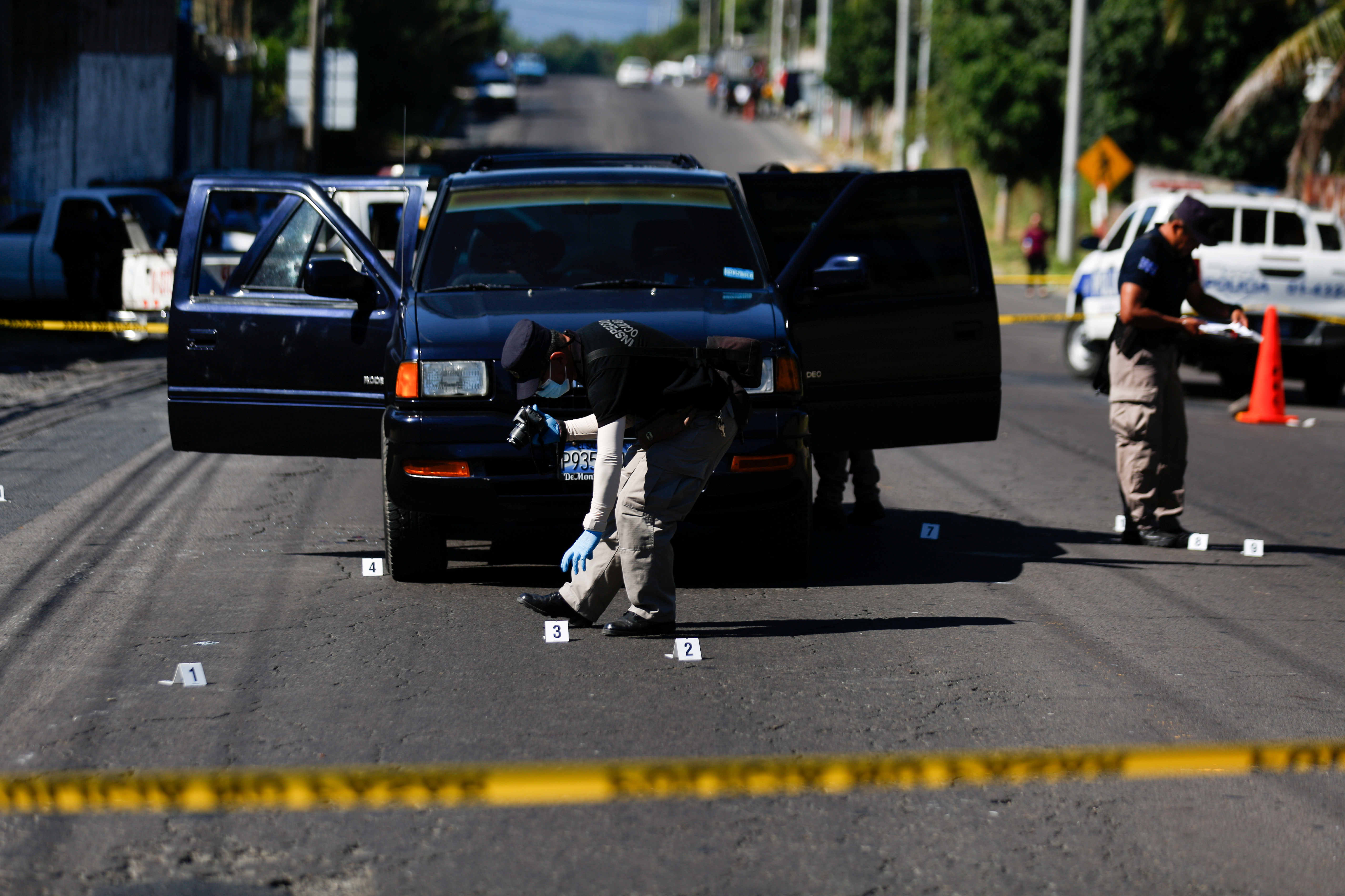 Police investigators collect evidence at a crime scene where a man was killed inside a car in San Martin
