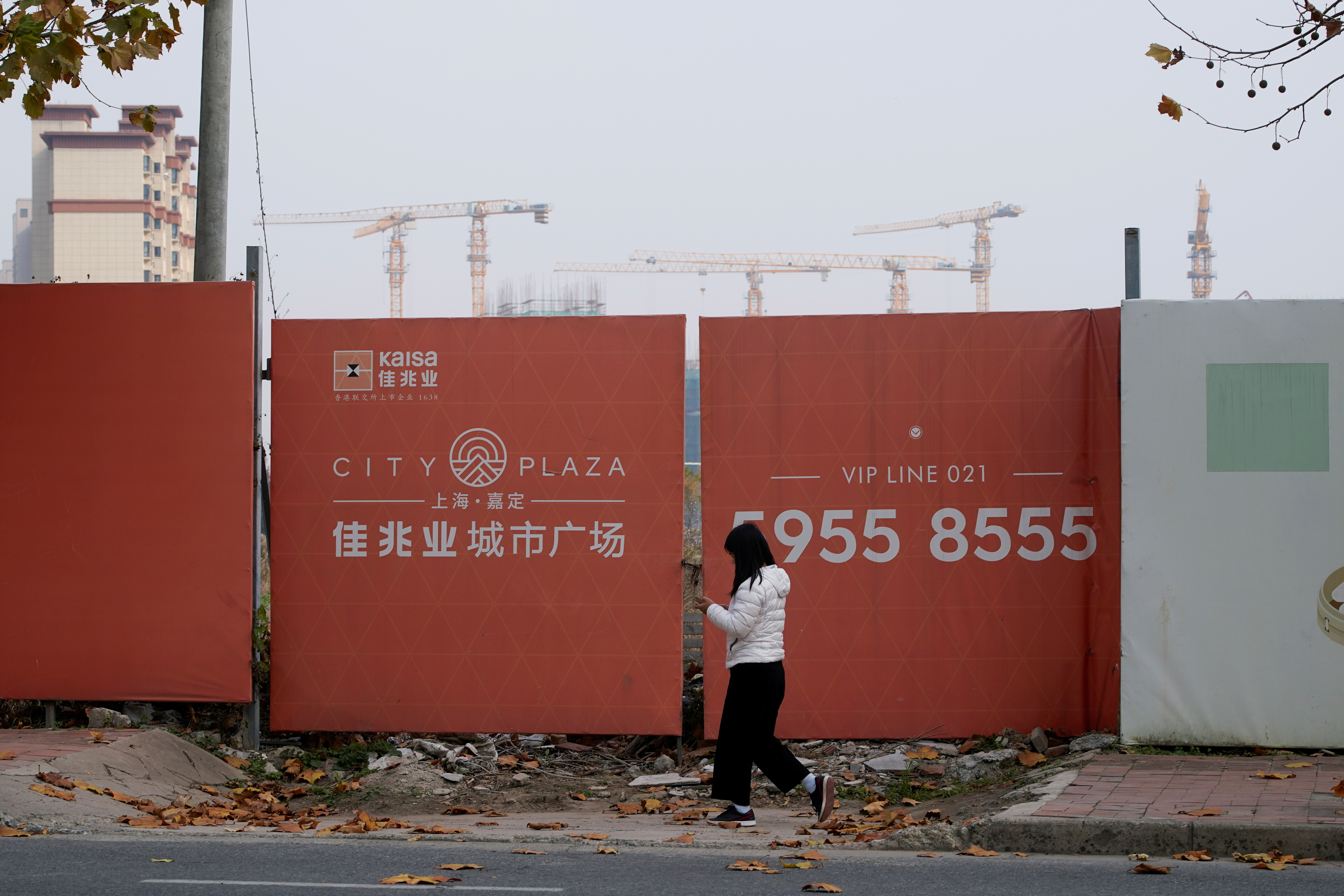 A woman walks past a construction site of Kaisa Group Holdings, in Shanghai