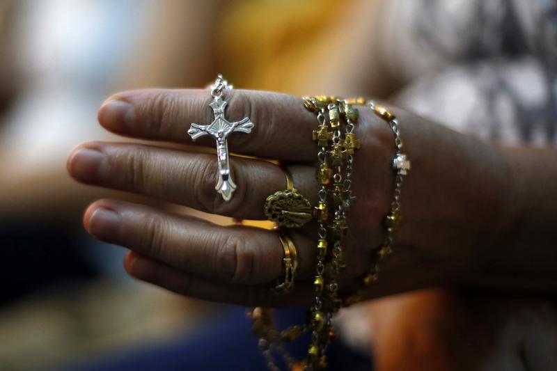 An Iraqi Christian woman holds a cross during a mass at the Church of the Virgin of Nasiriyah in Amman