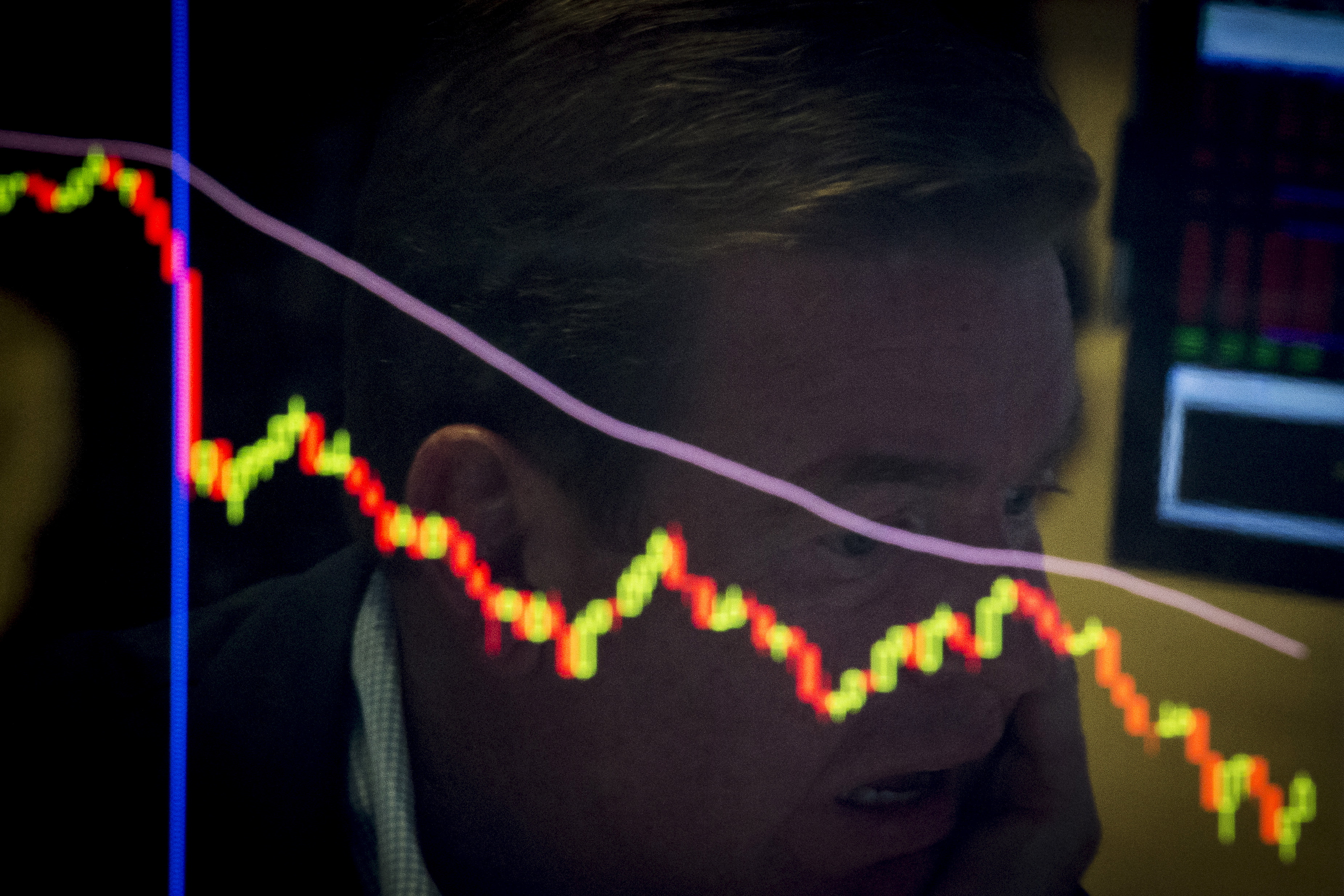 A specialist trader is reflected in a screen at his post on the floor of the New York Stock Exchange