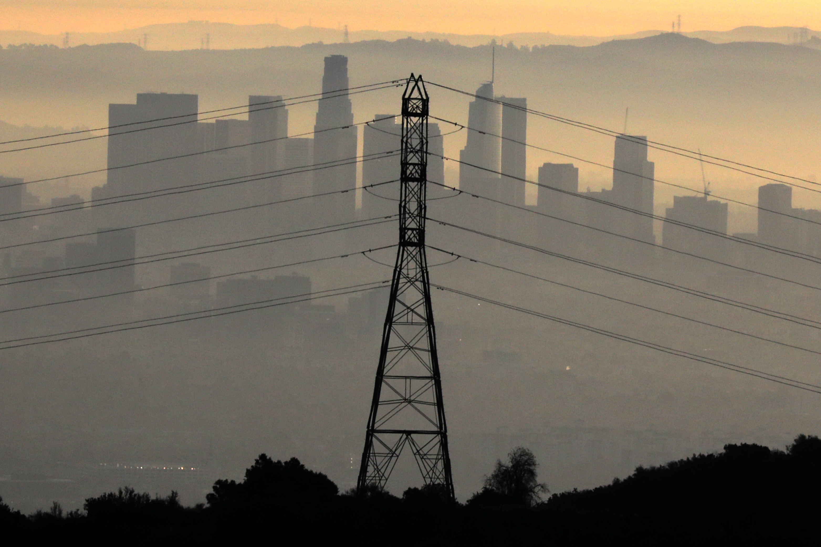 The downtown Los Angeles skyline is seen behind an electricity pylon at sunrise in Los Angeles
