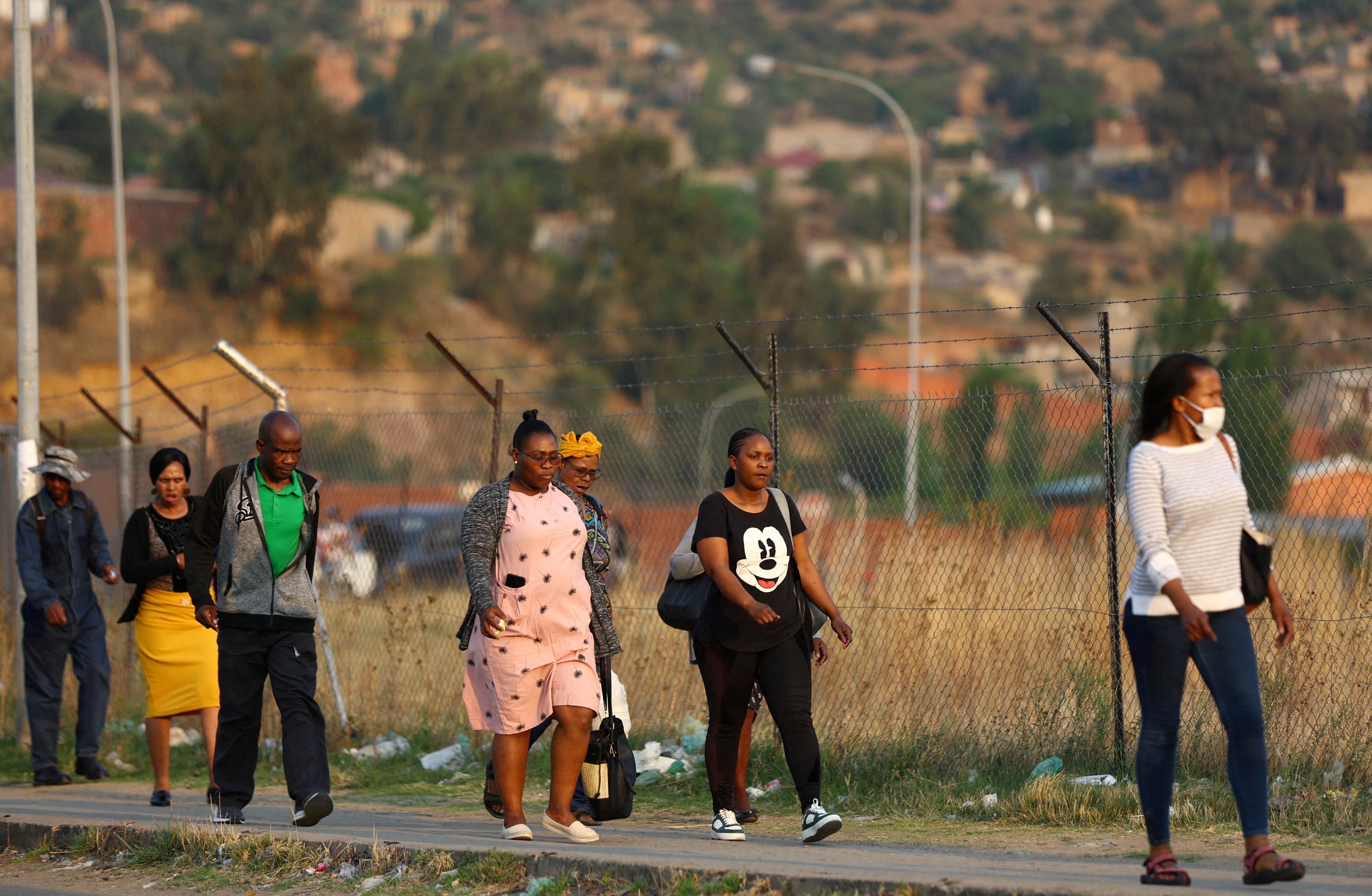 Factory workers walk home after work, ahead of the general elections, outside the capital Maseru in Lesotho