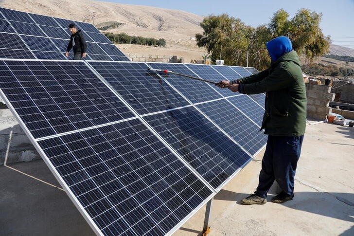 A worker cleans solar panels, which are one of the sustainable energy options that help olive farmers, in Mosul