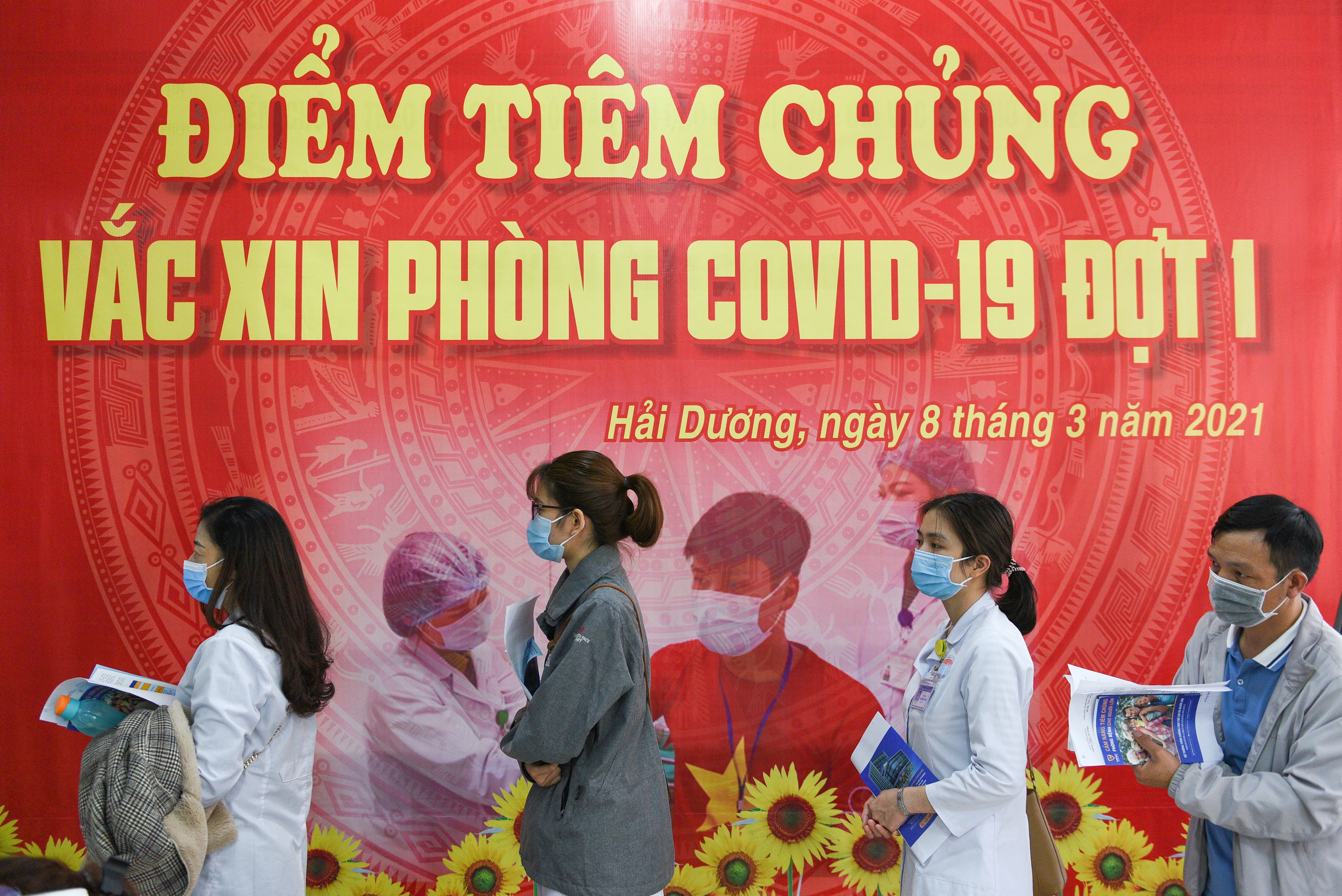 Health workers wait for their turn as Vietnam starts its official rollout of AstraZeneca's COVID-19 vaccine, in Hai Duong
