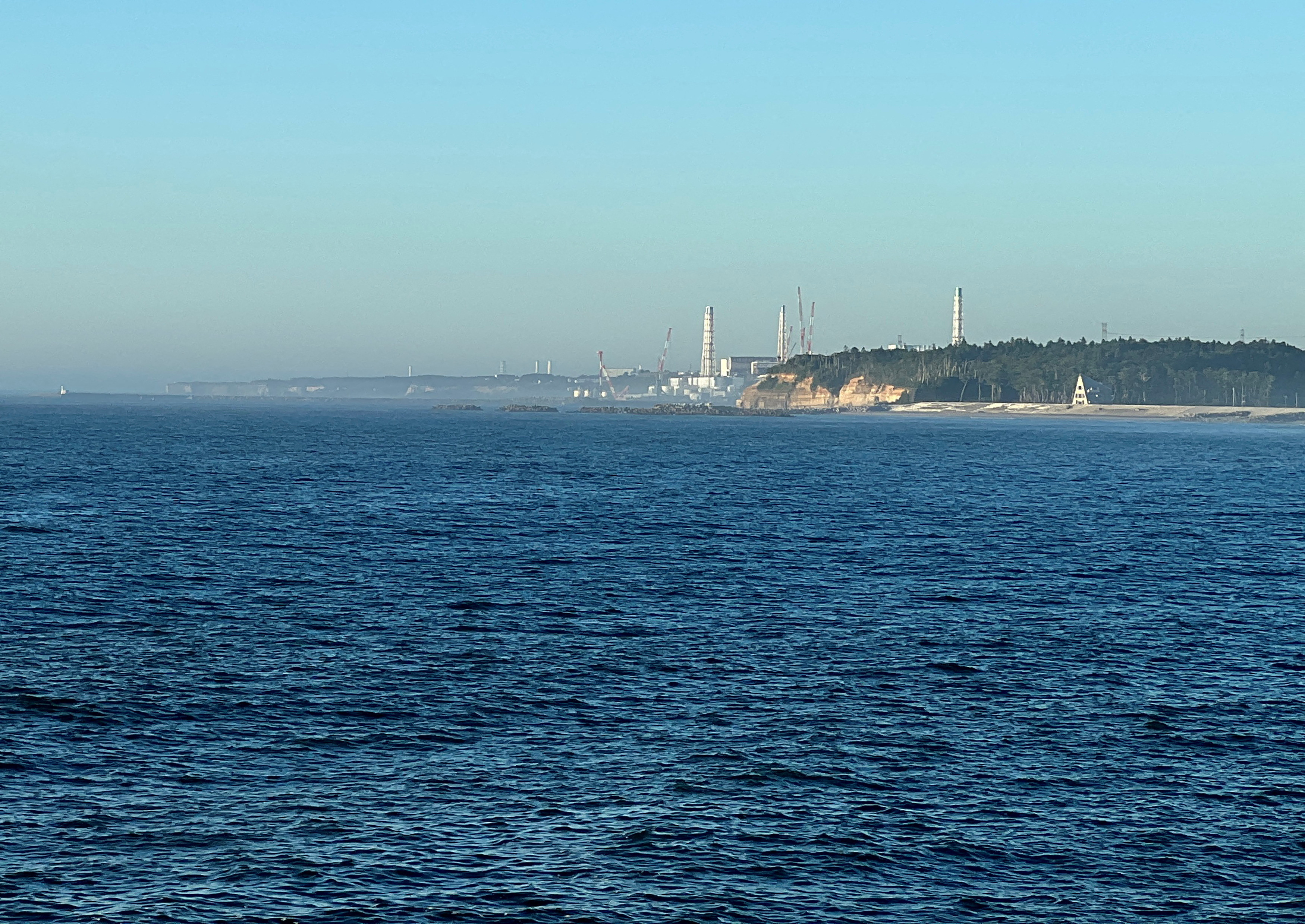 O vedere a centralei nucleare Fukushima Daiichi din portul de pescuit din apropiere Okido din orașul Nami