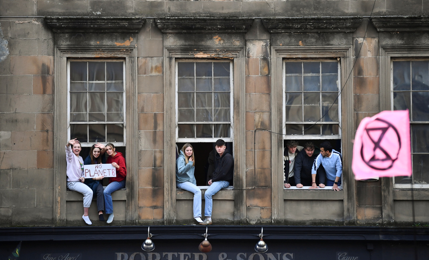 People sit in windows, of which some hold a placard, looking at the Fridays for Future march during the UN Climate Change Conference (COP26), in Glasgow, Scotland, Britain, November 5, 2021. REUTERS/Dylan Martinez