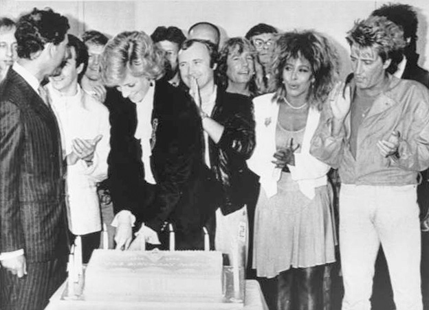 Prince Charles looks on as Princess Diana cuts a cake to mark the tenth year of the Prince's Trust at a charity rock concert at Wembley