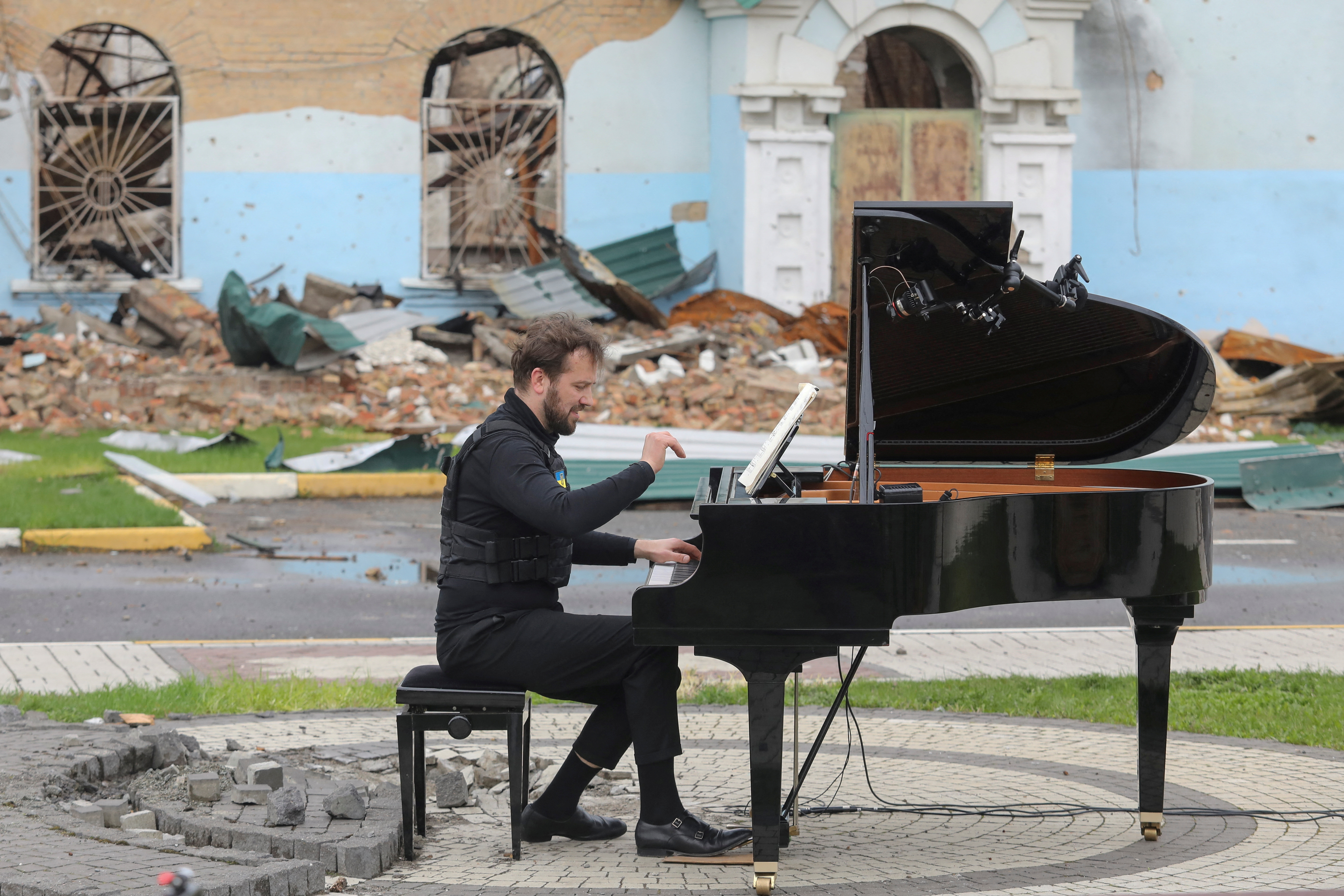 Lithuanian musician Mazintas plays a piano in front of the destroyed Central House of Culture in Irpin