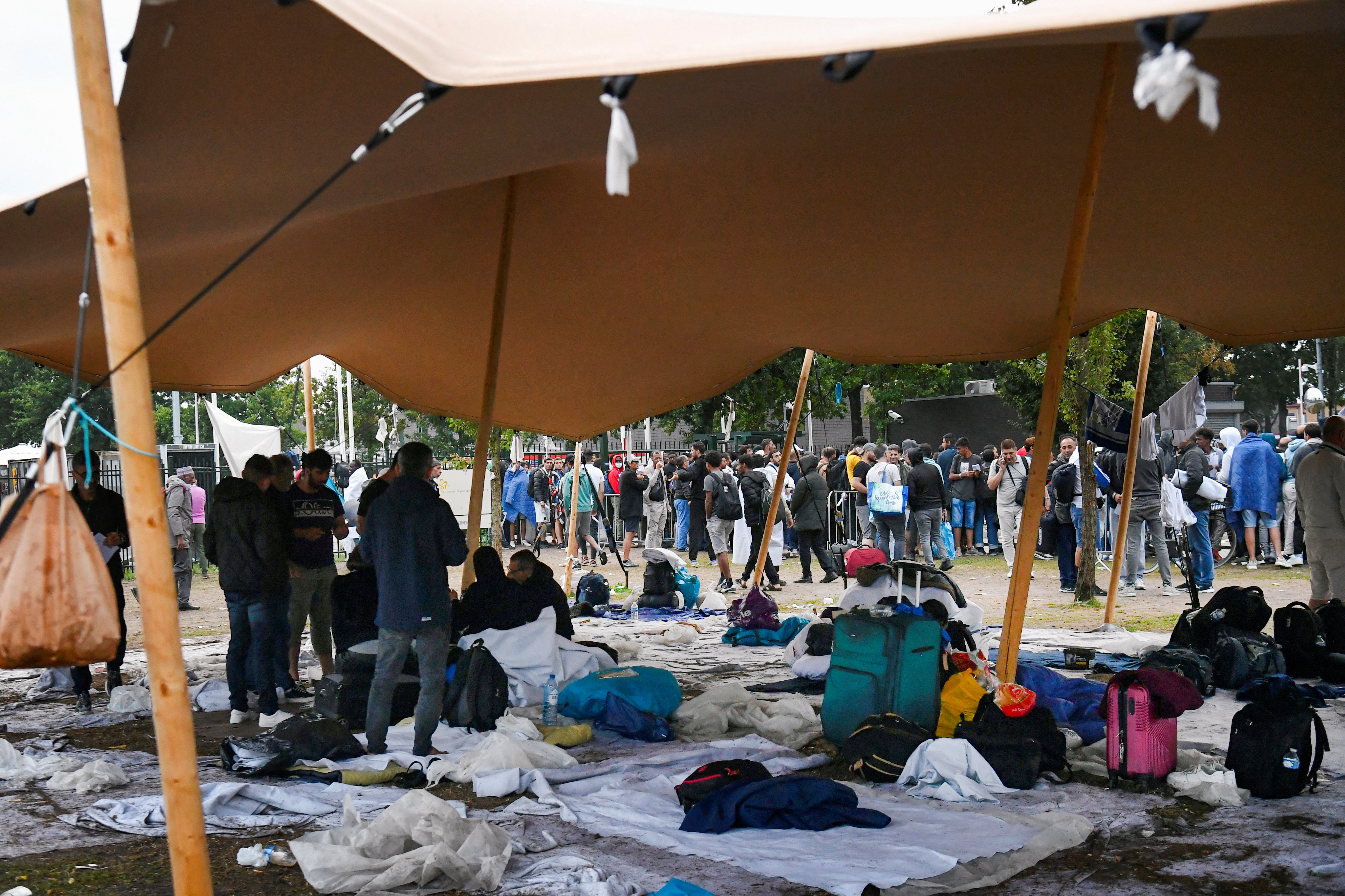 Refugees wait outdoors on the damp ground at the main reception centre for asylum seekers, in Ter Apel