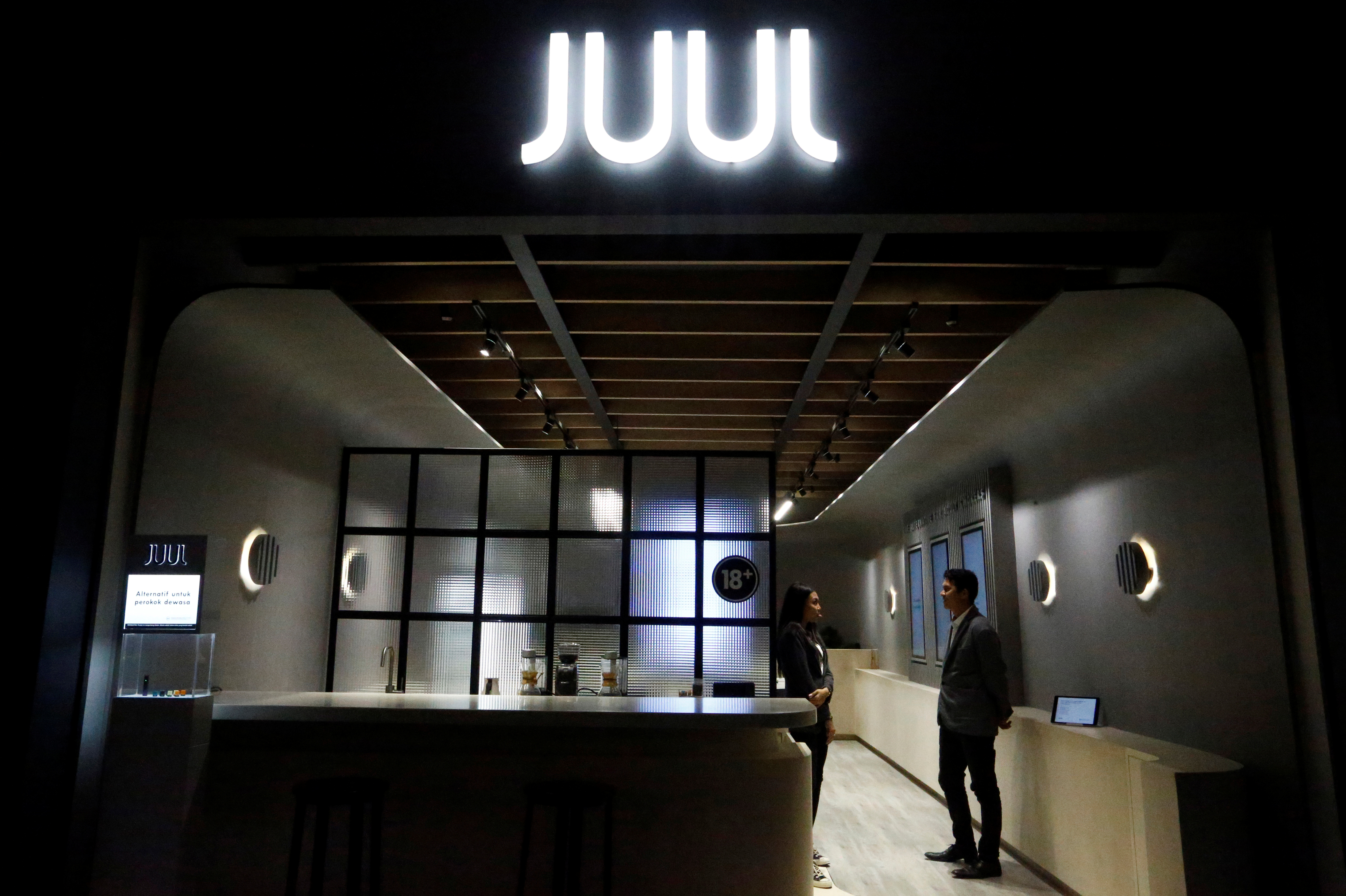 Shopkeepers stand inside a Juul shop at a shopping mall in Jakarta